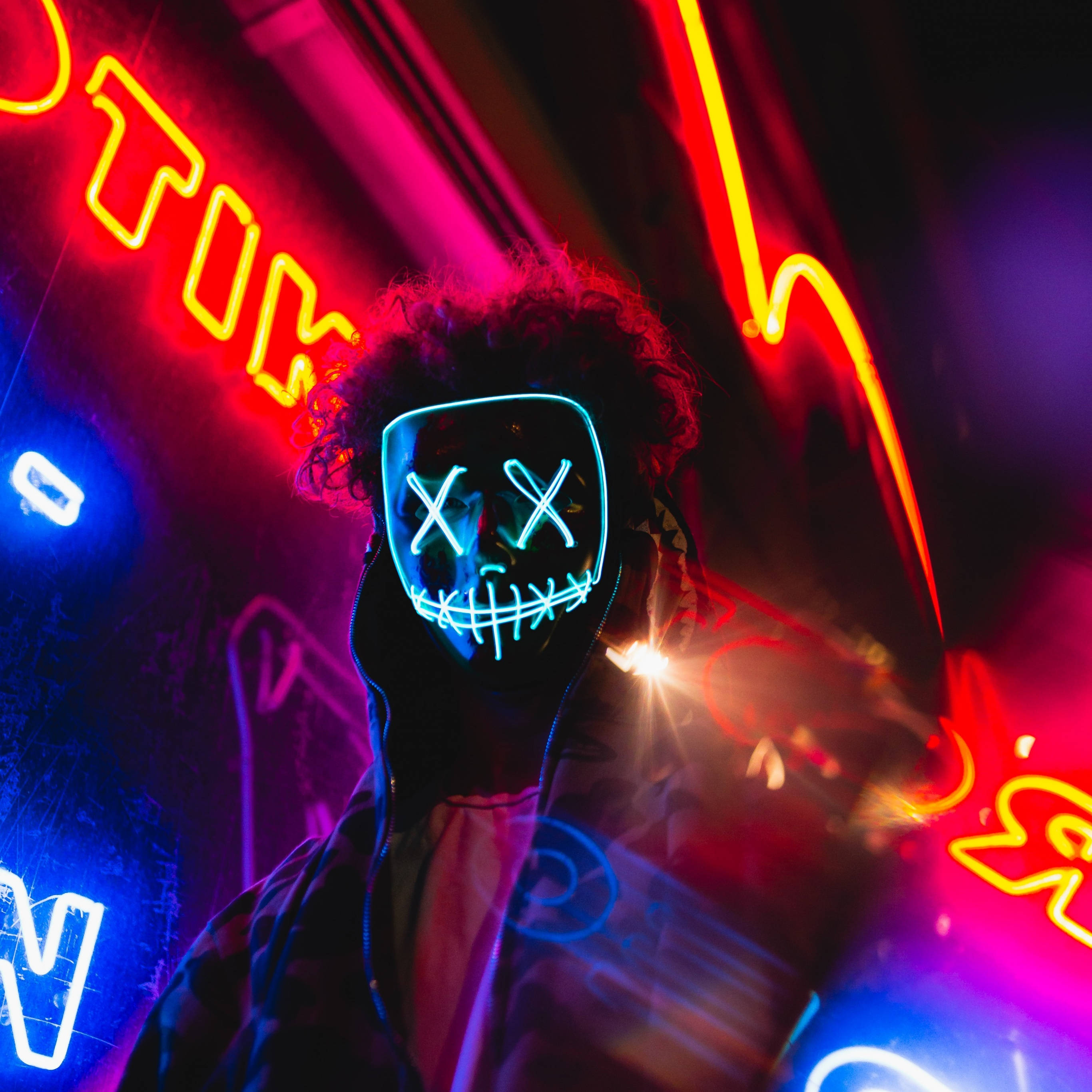 glowing blue LED mask, vibrant red and blue neon signs, dark club setting, 2K Desktop Wallpaper