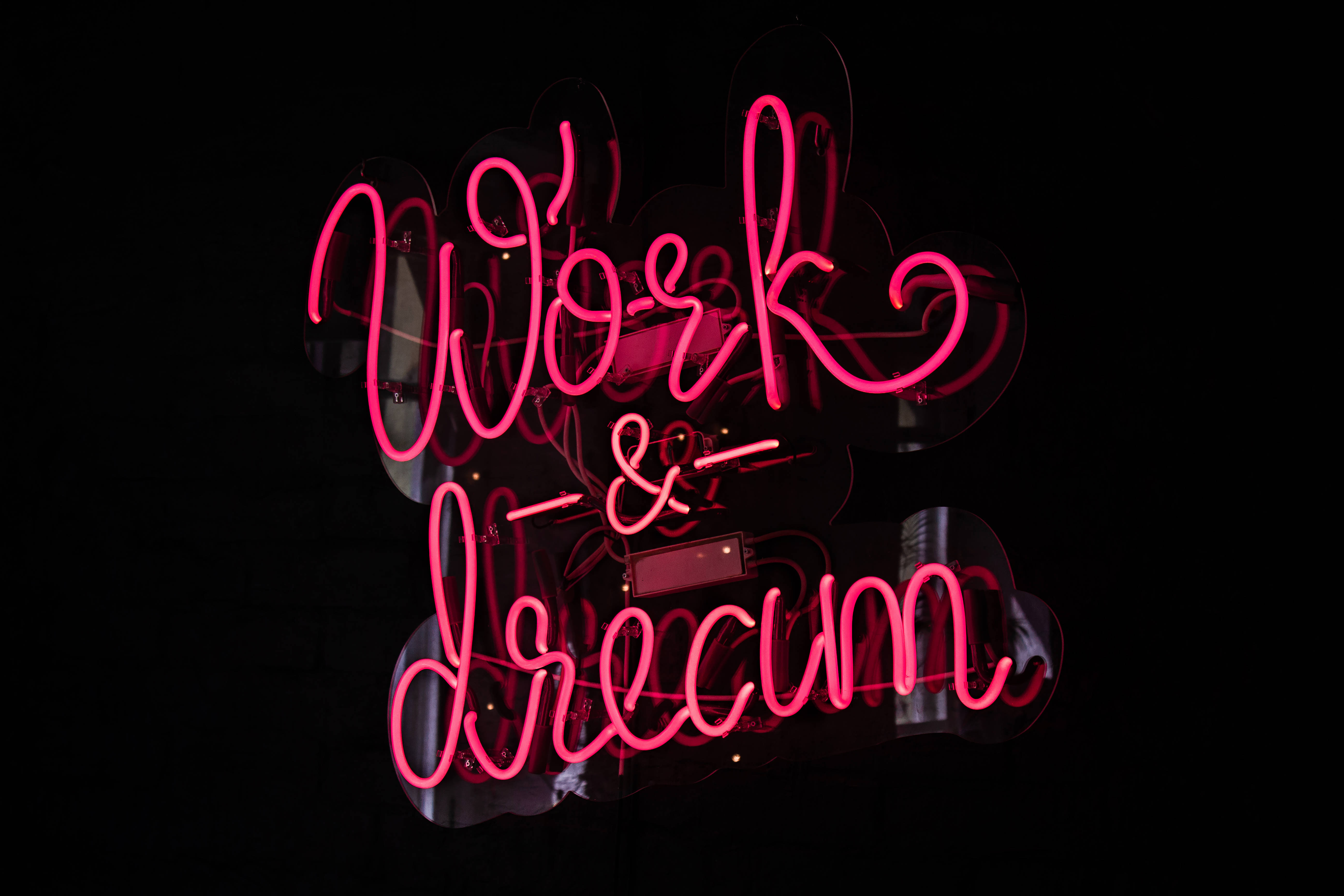 Work & Dream, glowing pink neon sign, dark background, 5K Desktop Wallpaper