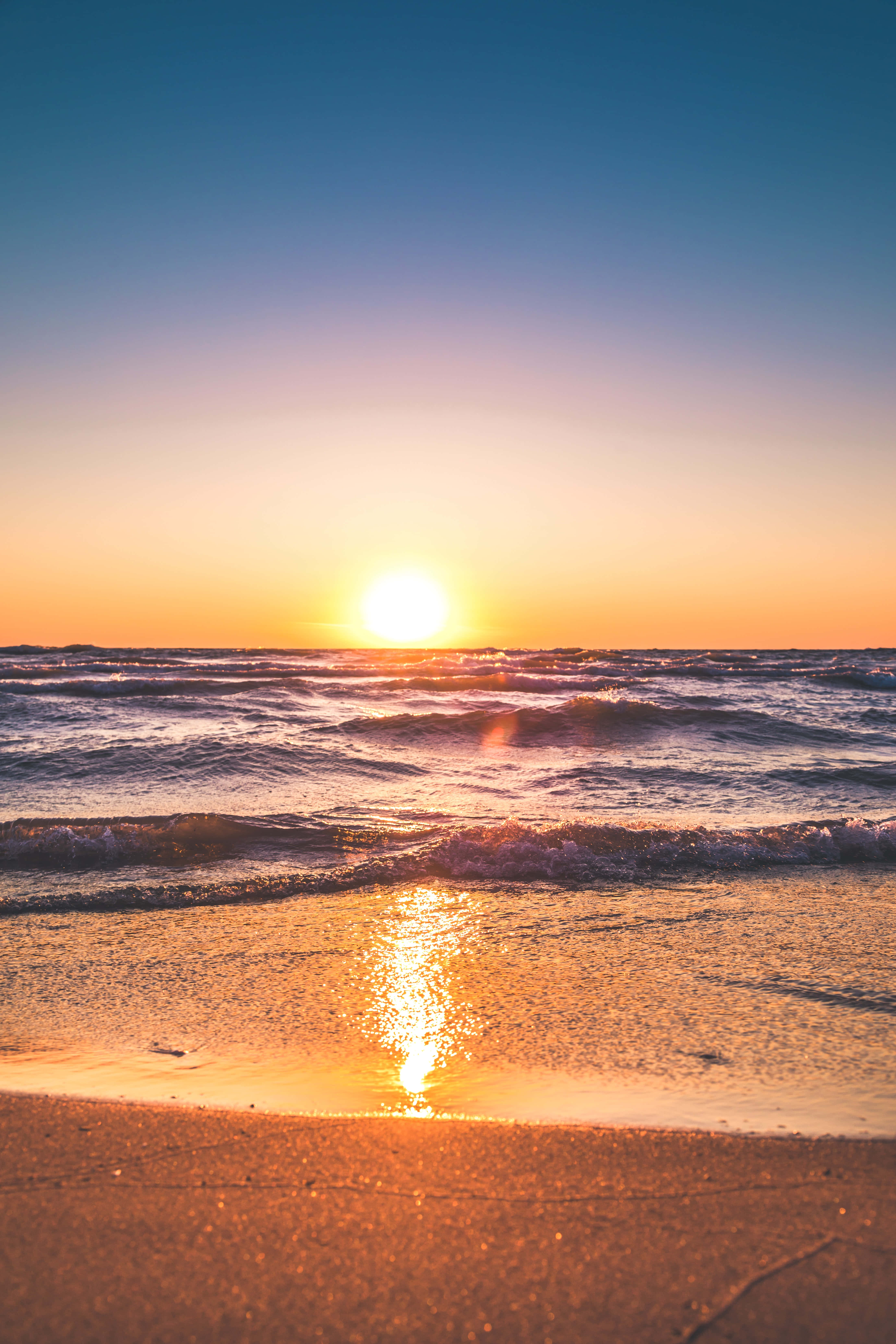 Golden sunset, vibrant orange and blue gradient sky, ocean waves, 5K Phone Wallpaper