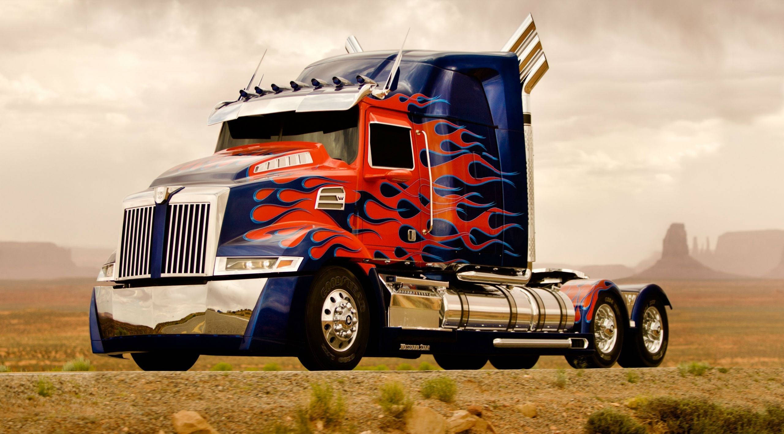 red and blue flame-painted semi-truck, chrome accents, desert landscape, 2K Desktop Wallpaper