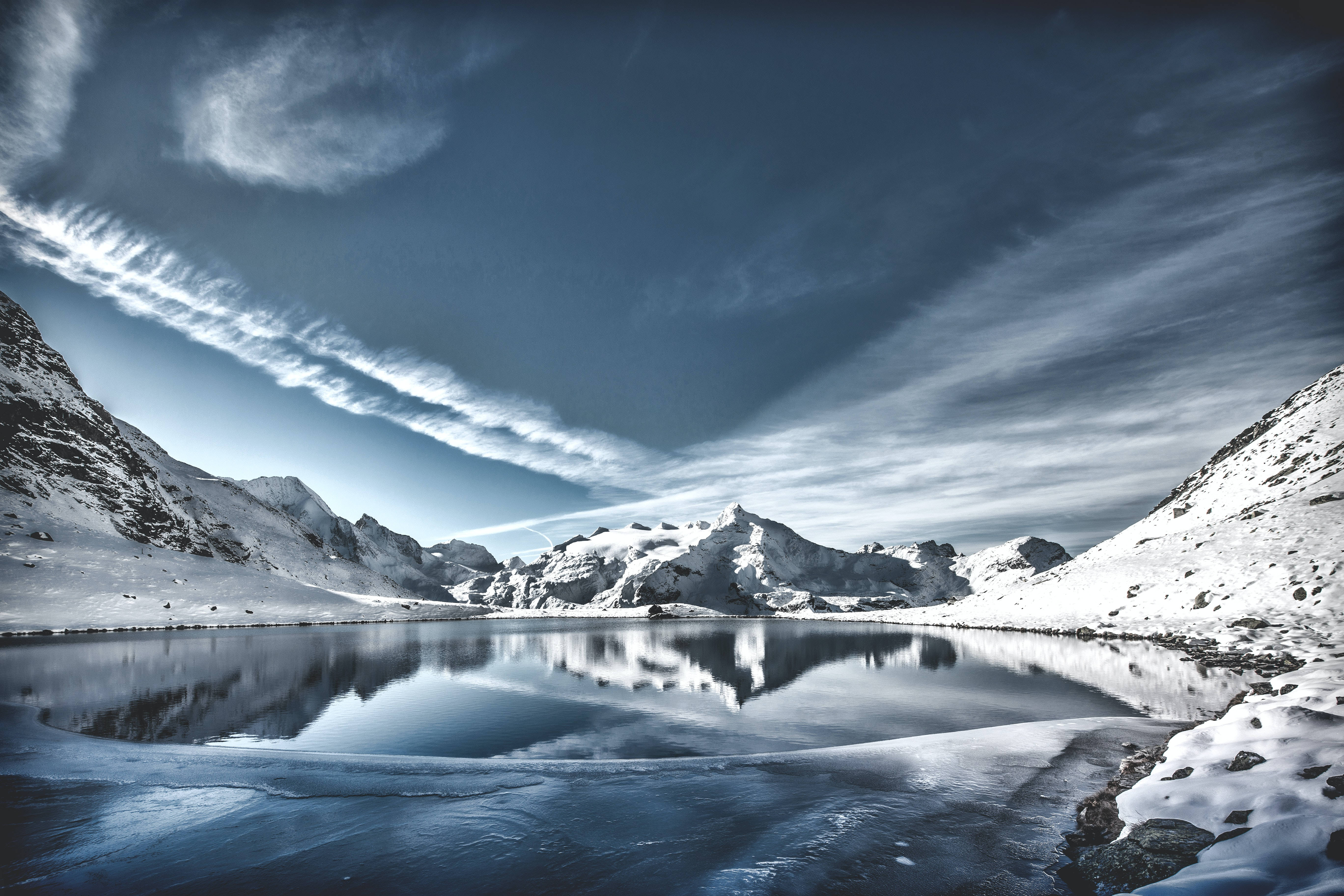 frozen mountain lake, snow-capped peaks, dramatic cloudy sky, 5K Desktop Wallpaper