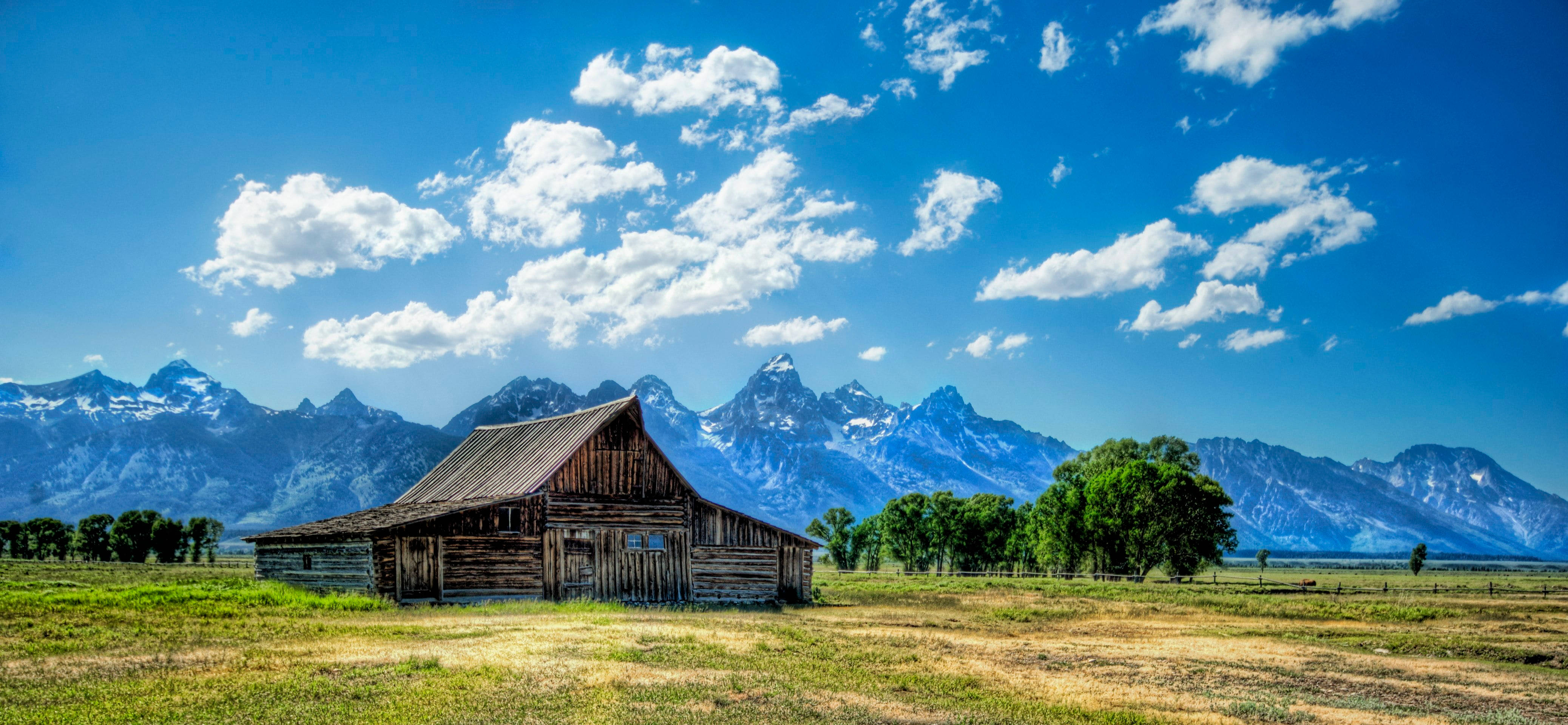 wooden barn, sunlit field, snow-capped mountains, 4K Desktop Wallpaper