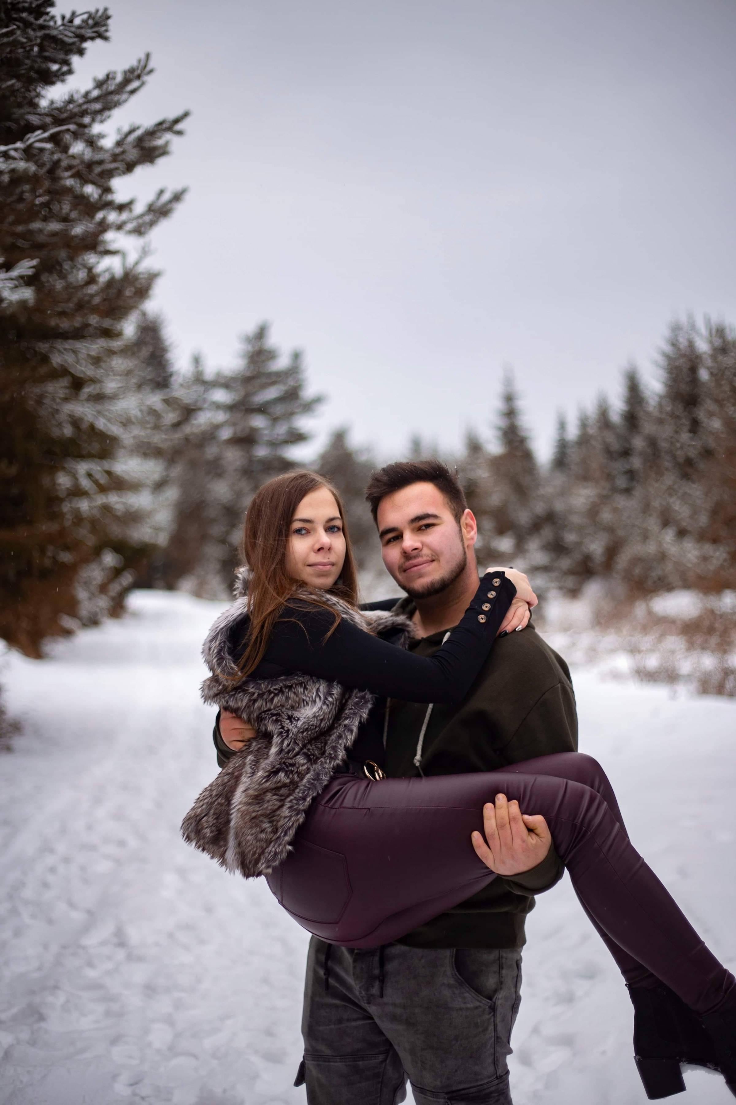 couple hugging, bridal carry position, snowy forest path, 2K Phone Wallpaper