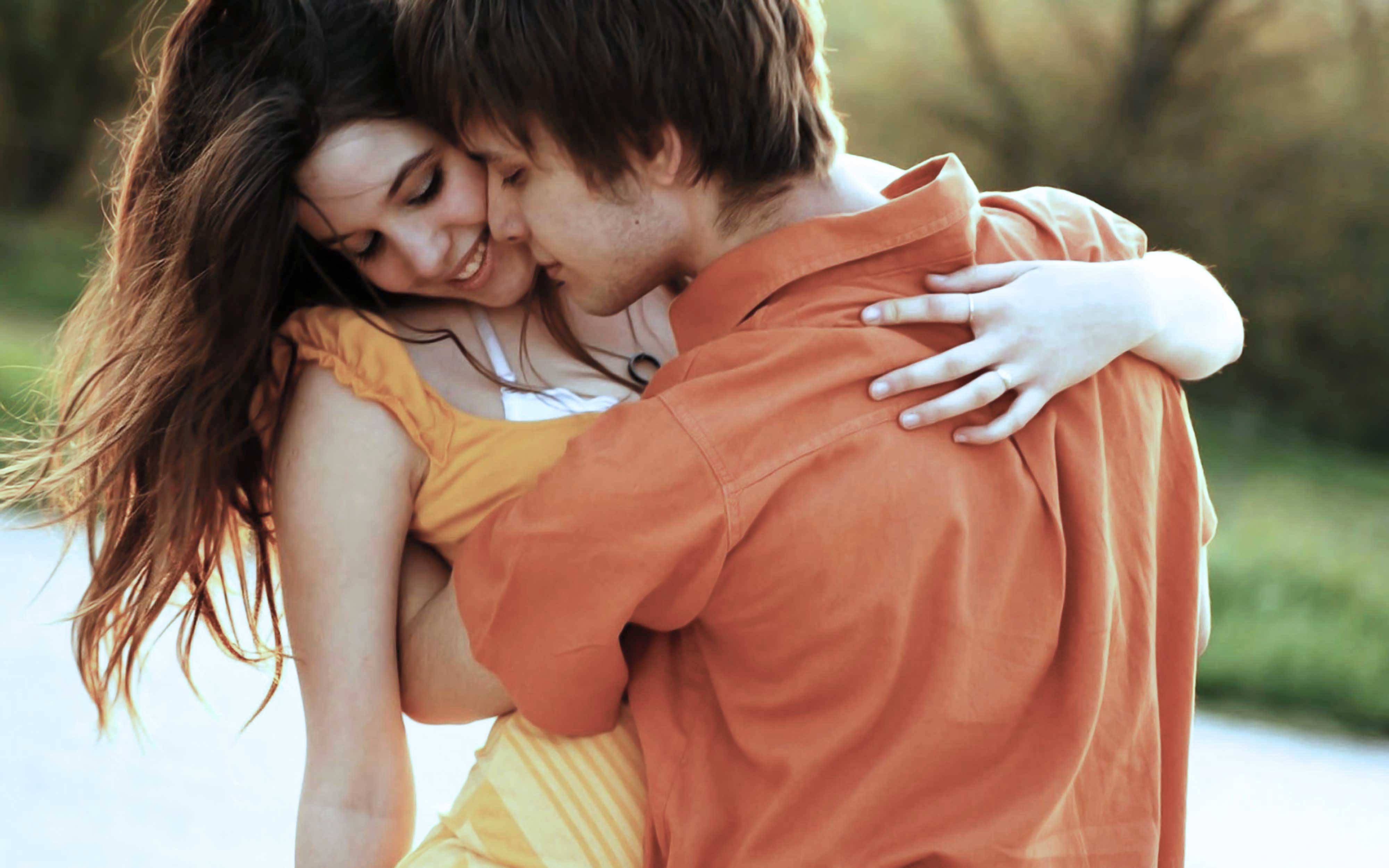 young hugging couple, sunlit outdoor setting, soft golden light, 4K Desktop Wallpaper