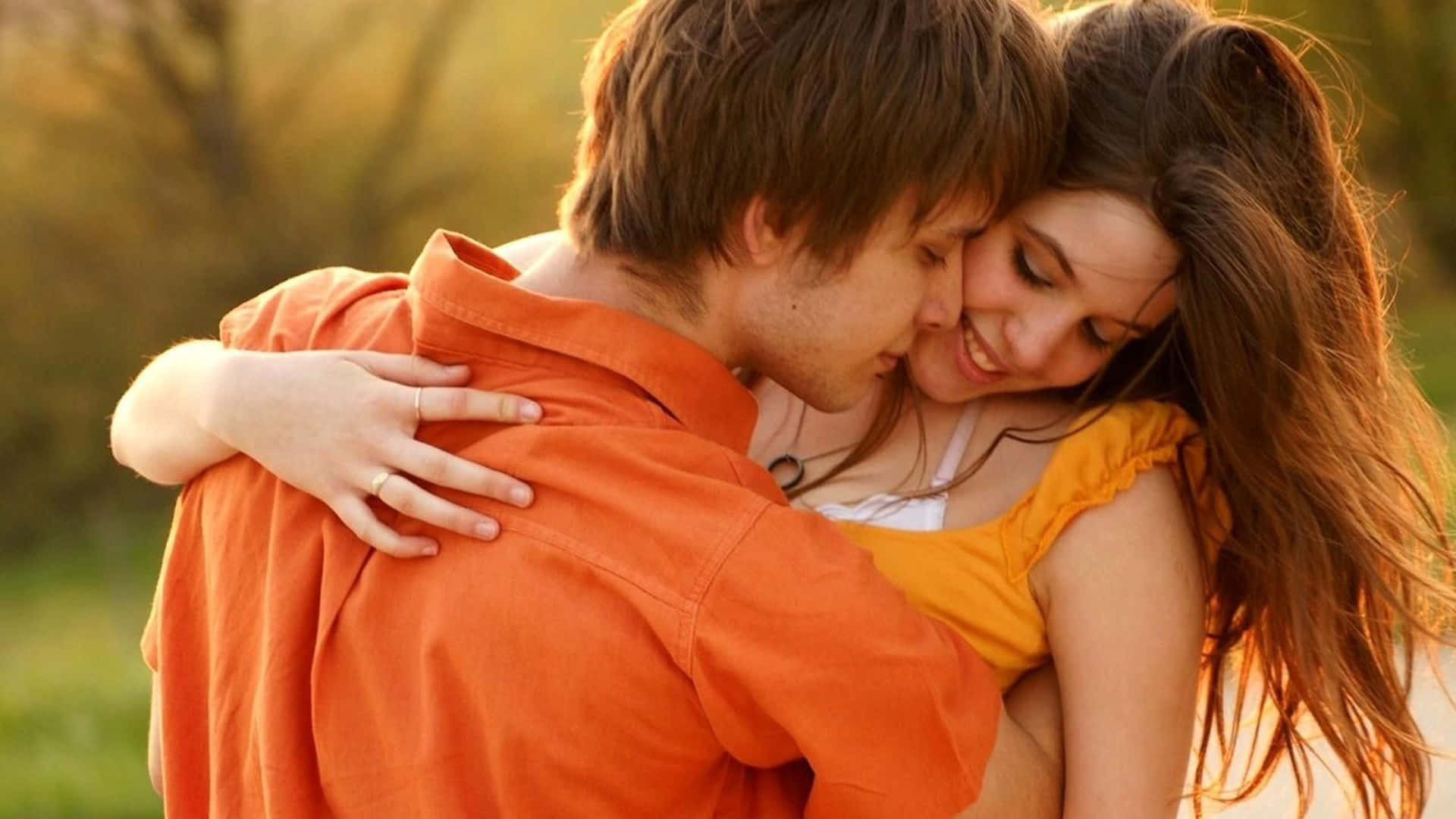 affectionate couple embrace outdoors, golden sunlight, blurred greenery, Full HD Desktop Wallpaper