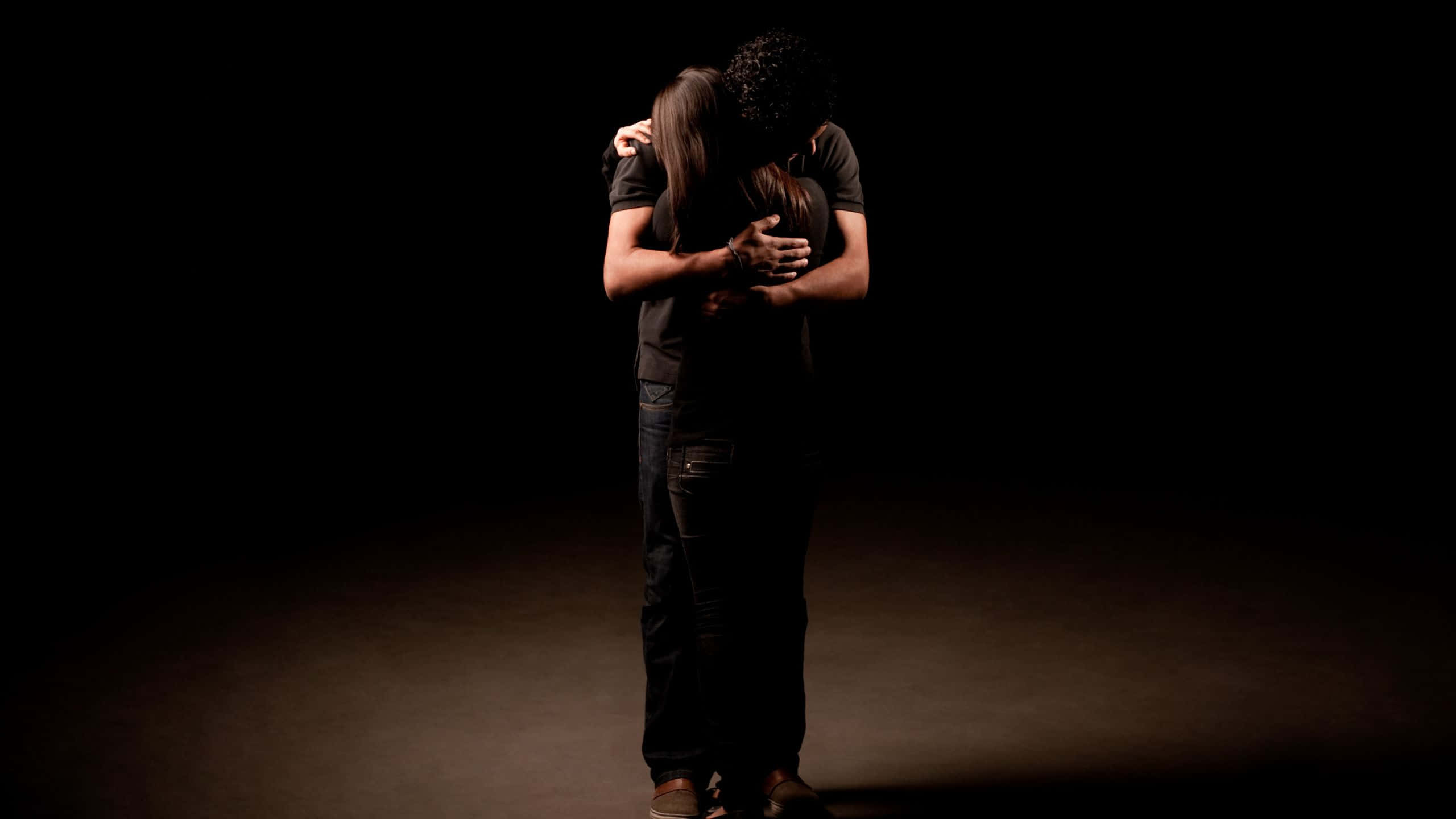 dark hugging sad couple, dimly lit studio, dramatic spotlighting, 2K Desktop Wallpaper