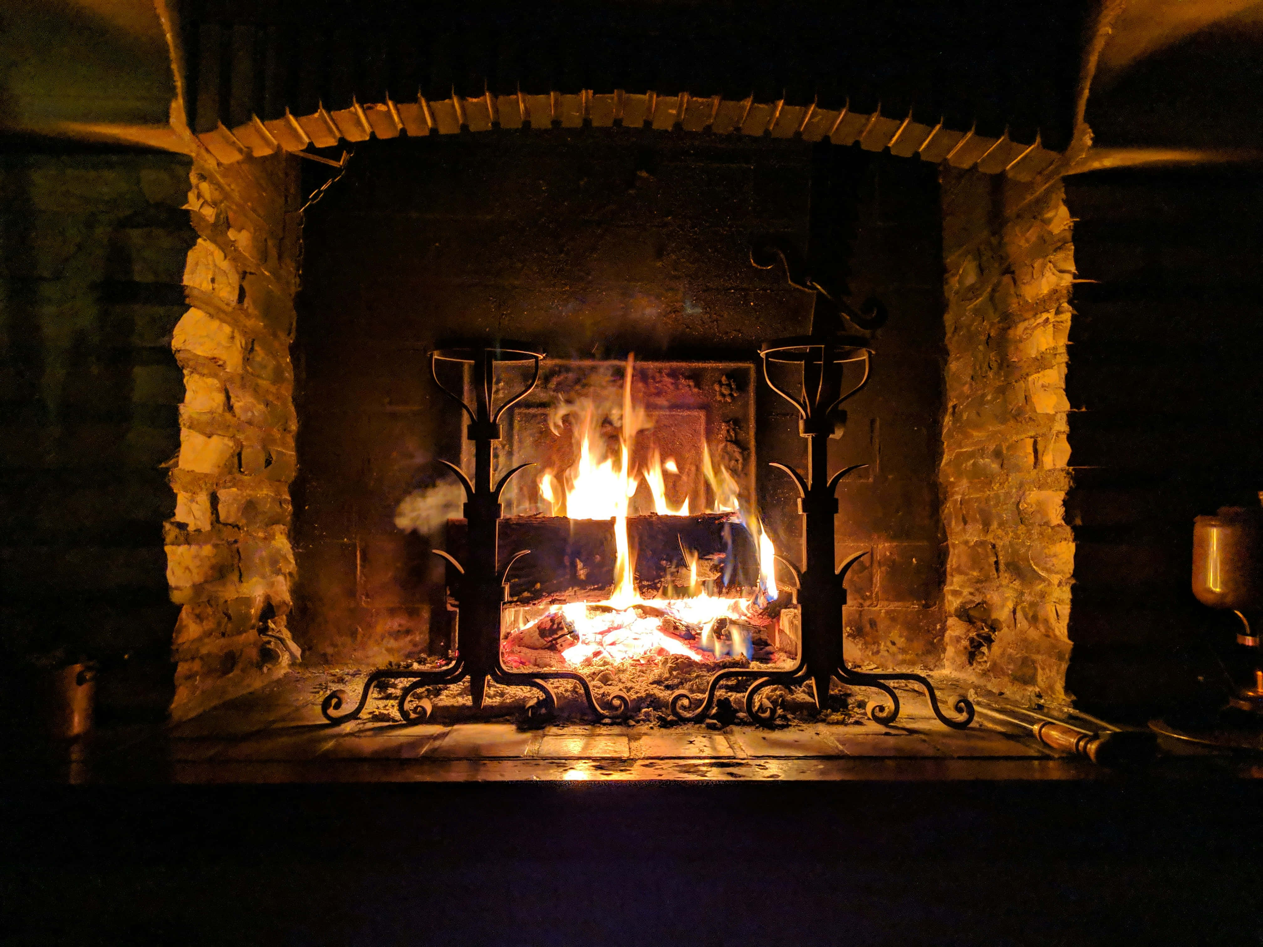 rustic stone fireplace, weathered bricks, ornate black iron tools, 4K Desktop Wallpaper