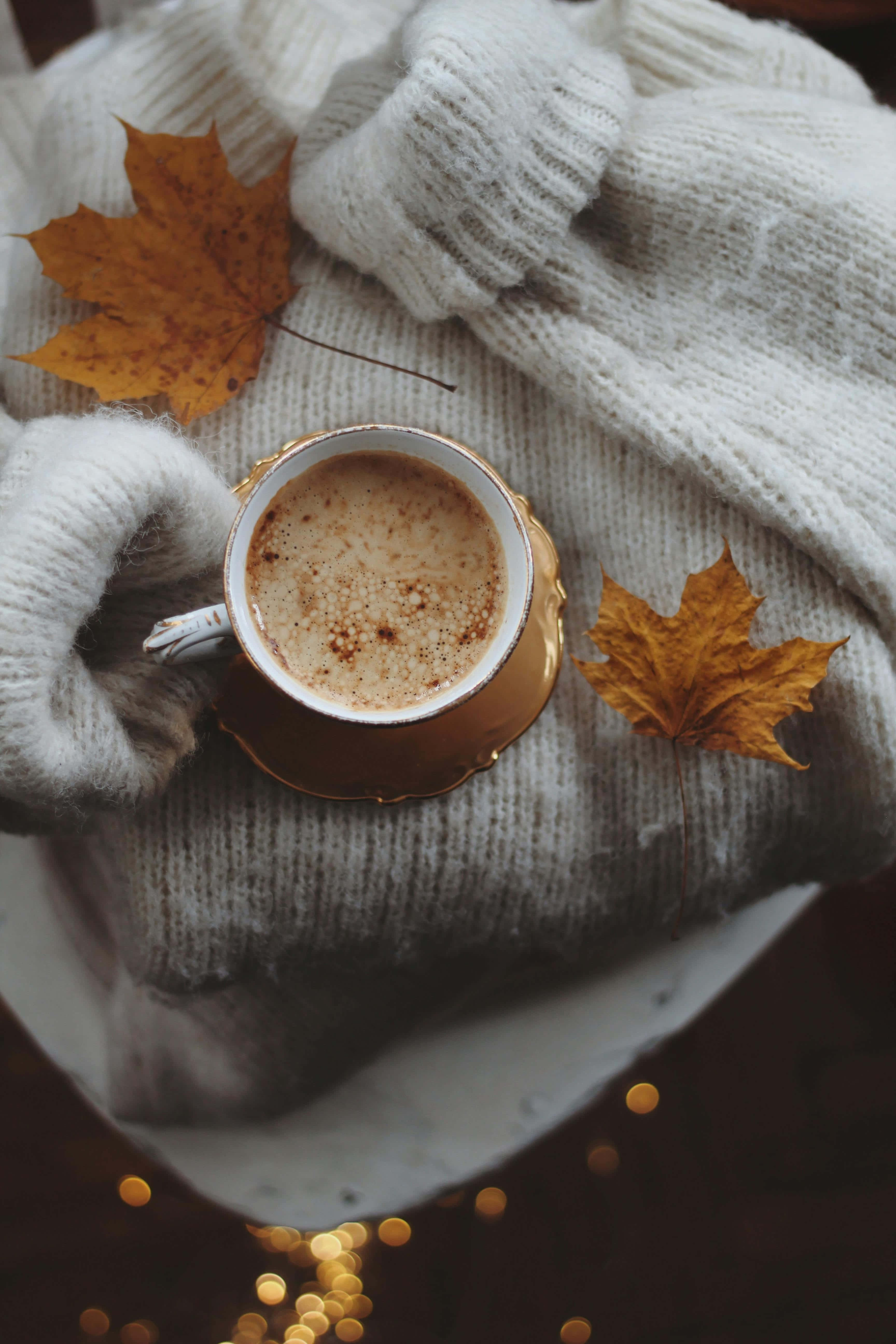 golden cup of spiced coffee, soft white knit sweater, autumn maple leaves, 5K Phone Wallpaper