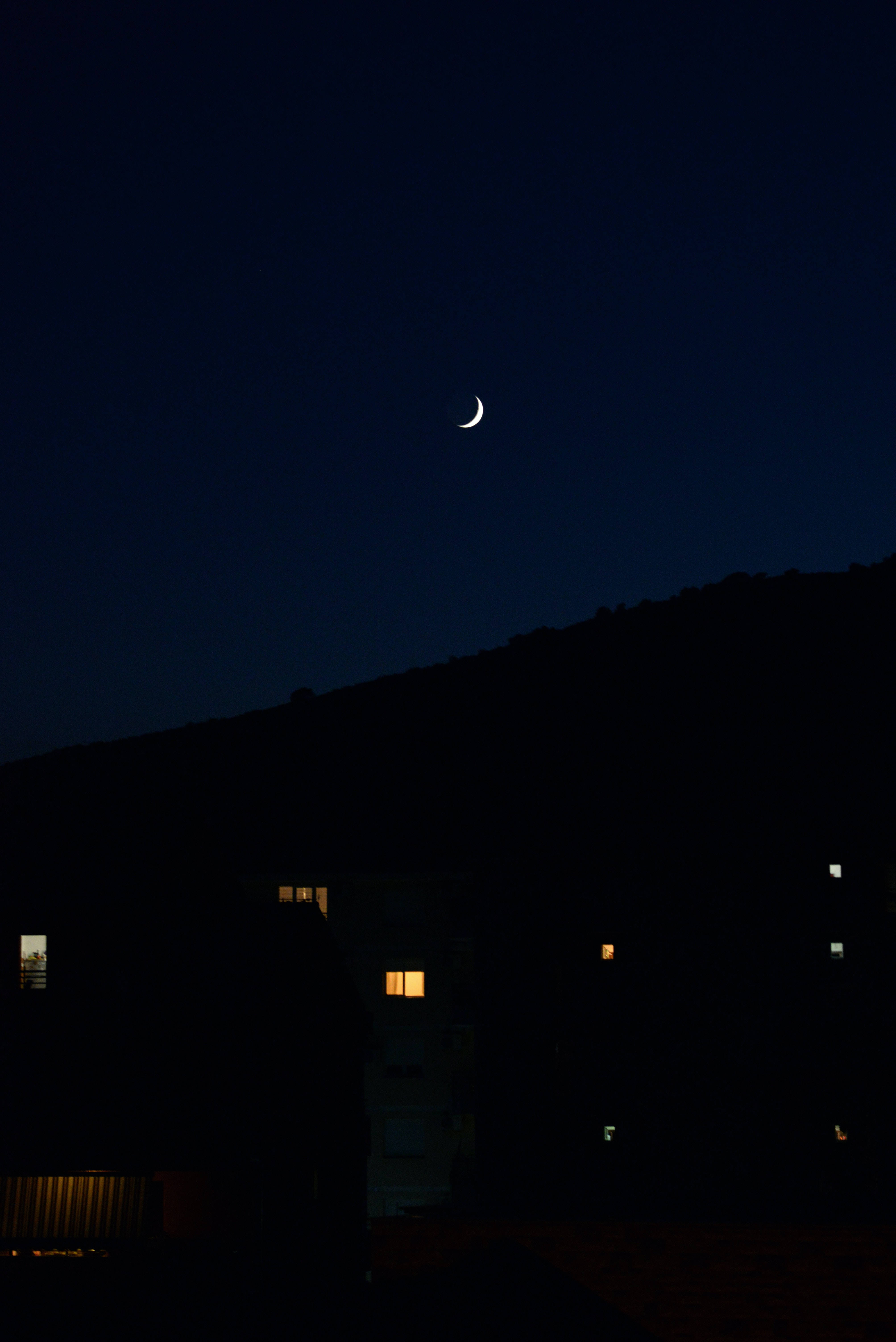 crescent moon, dark hillside, warm lights, 5K Phone Wallpaper
