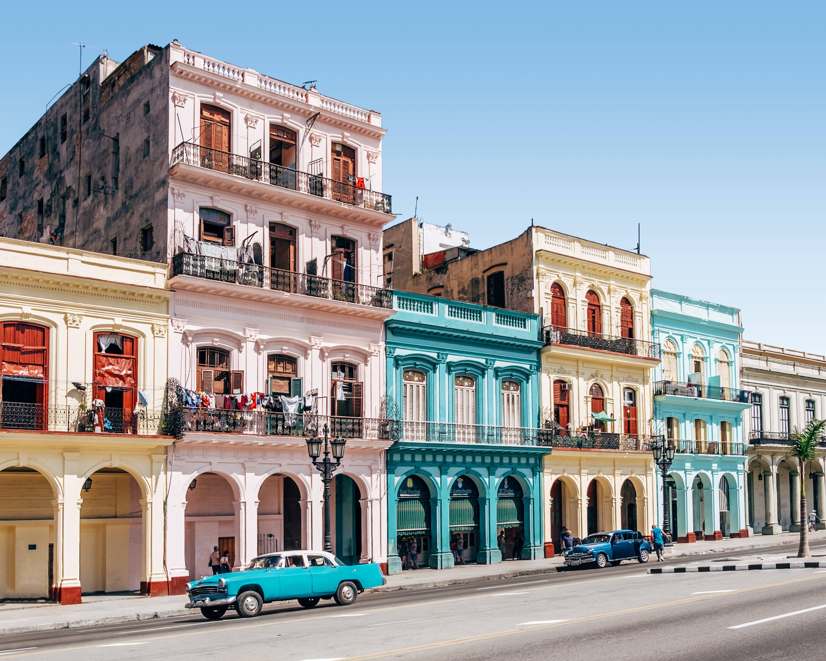pastel-colored colonial buildings, sunlit street, classic American cars, 2K Desktop Wallpaper