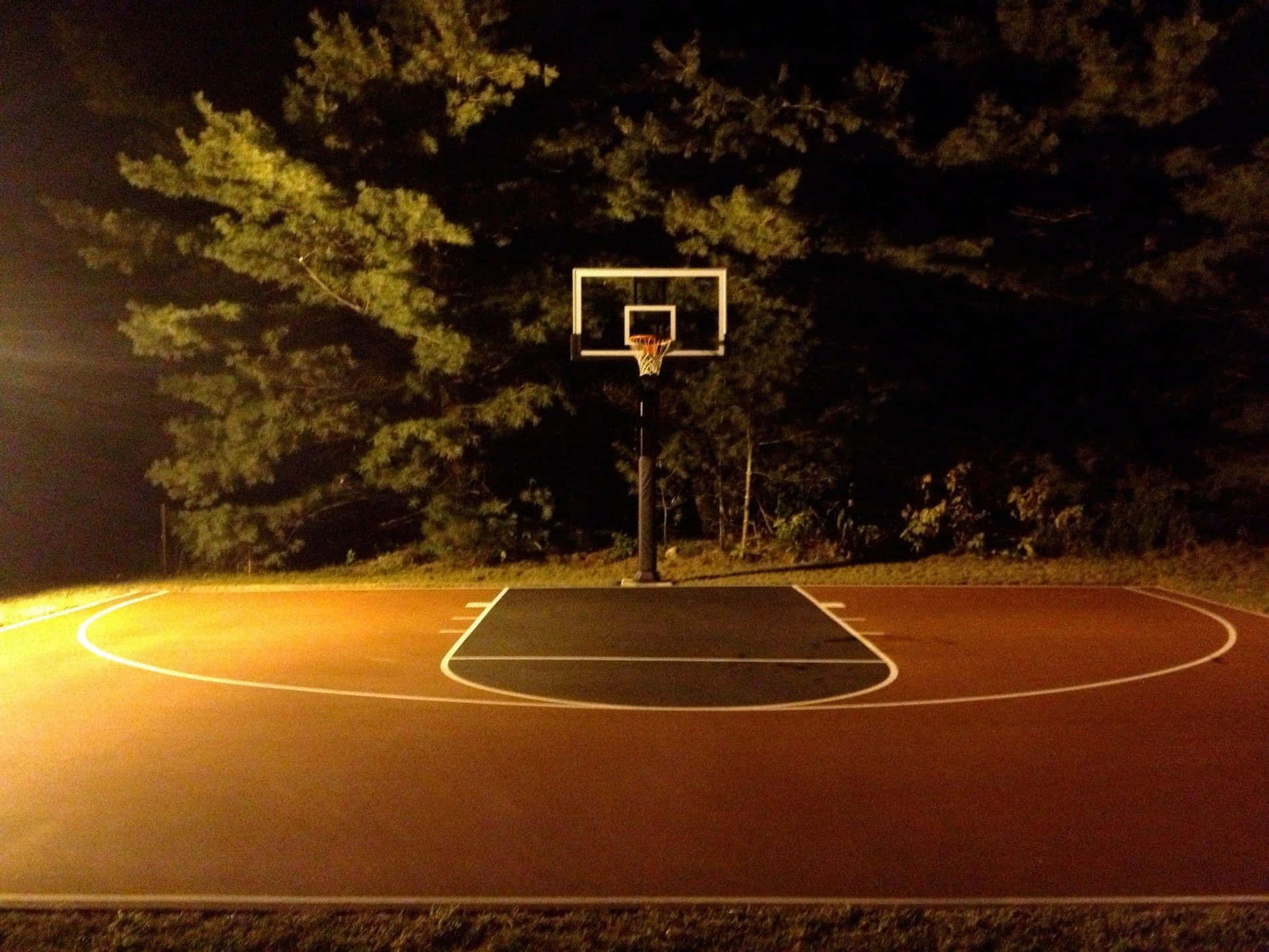 nighttime outdoor basketball court, warm artificial light, dark trees, Full HD Desktop Wallpaper