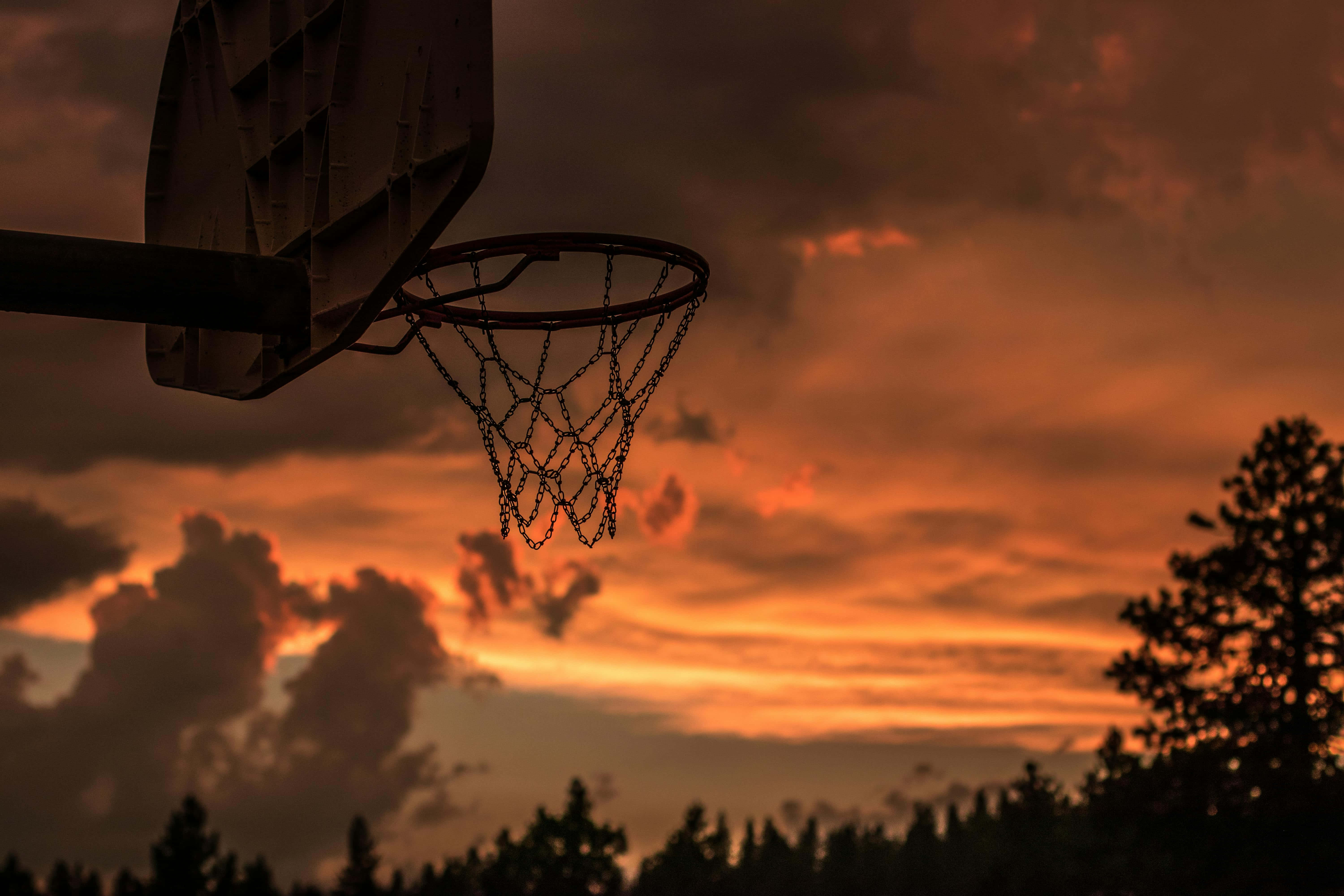 sunset basketball hoop silhouette, fiery orange and red sunset sky, dark clouds, 5K Desktop Wallpaper