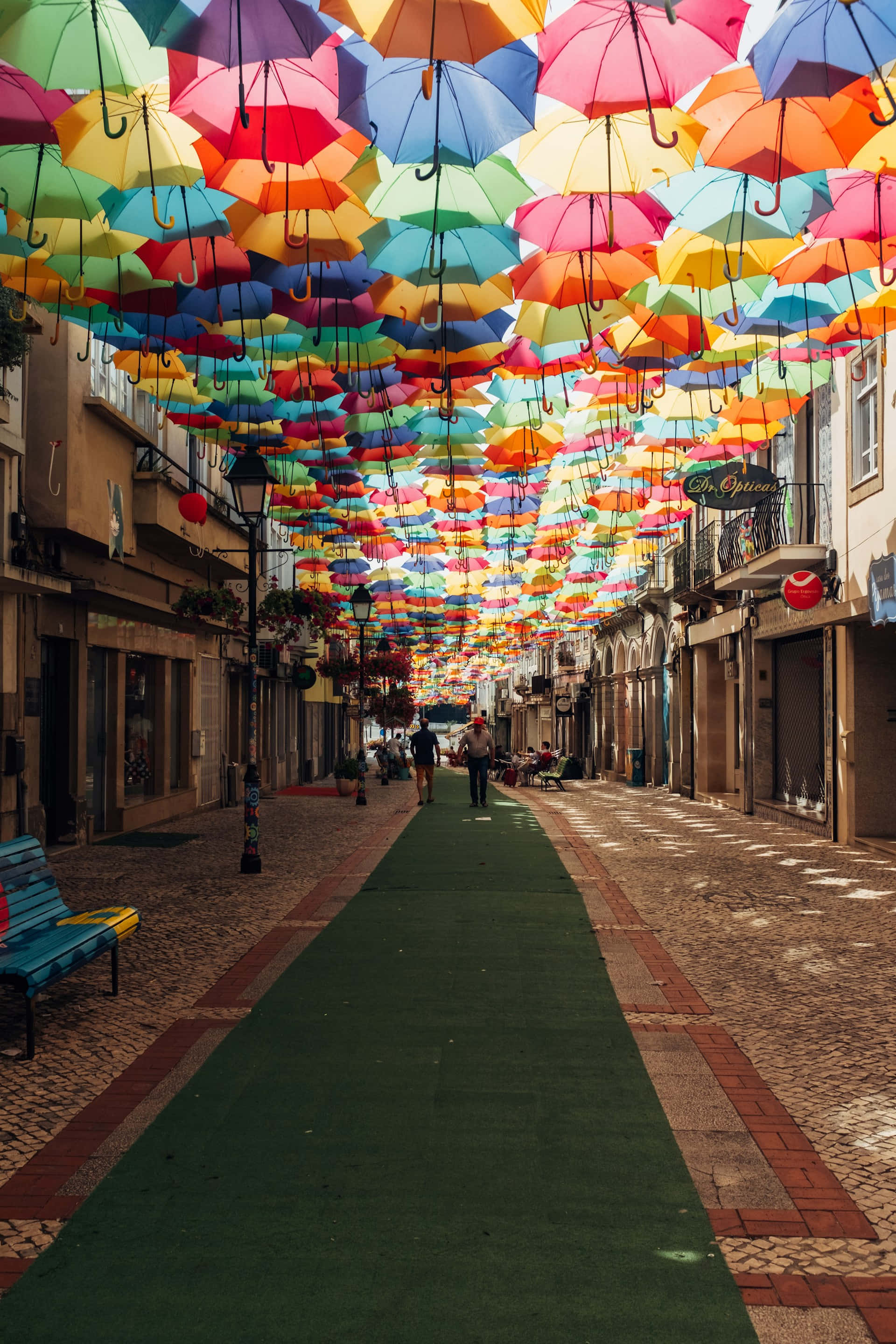 colorful umbrella canopy, rainbow tunnel, cobblestone walkway, 2K Phone Wallpaper