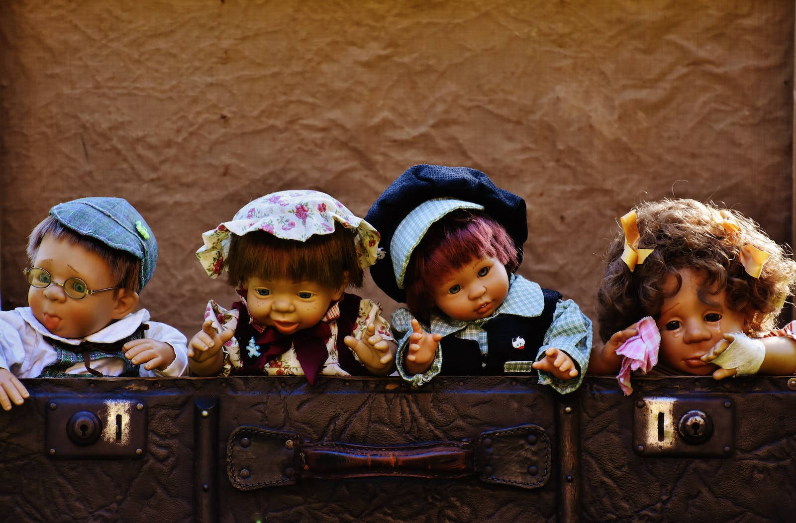 four cute dolls, worn leather suitcase, textured brown wall, HD Desktop Wallpaper