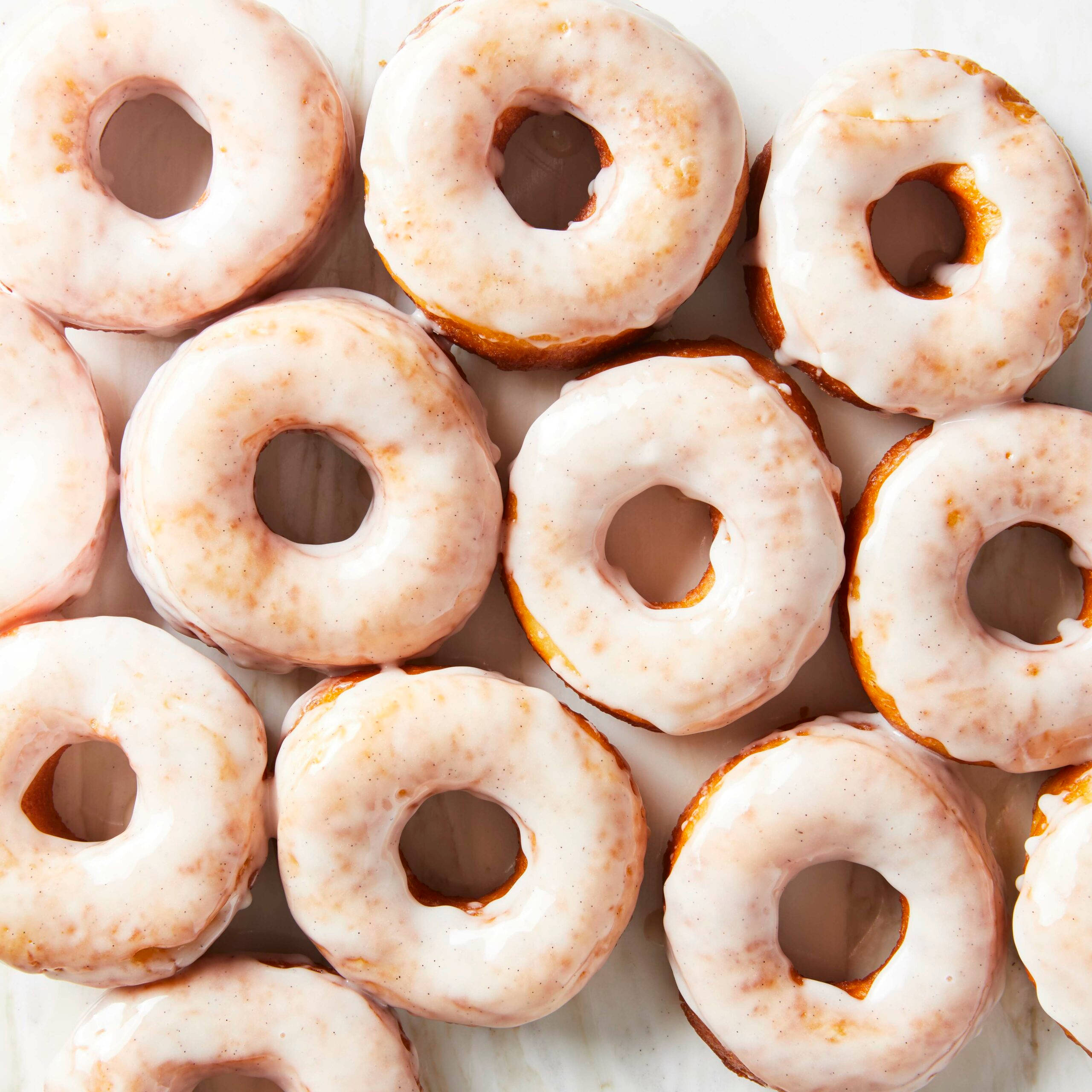 fresh white glazed donuts, cinnamon sugar coating, white marble surface, 2K Desktop Wallpaper