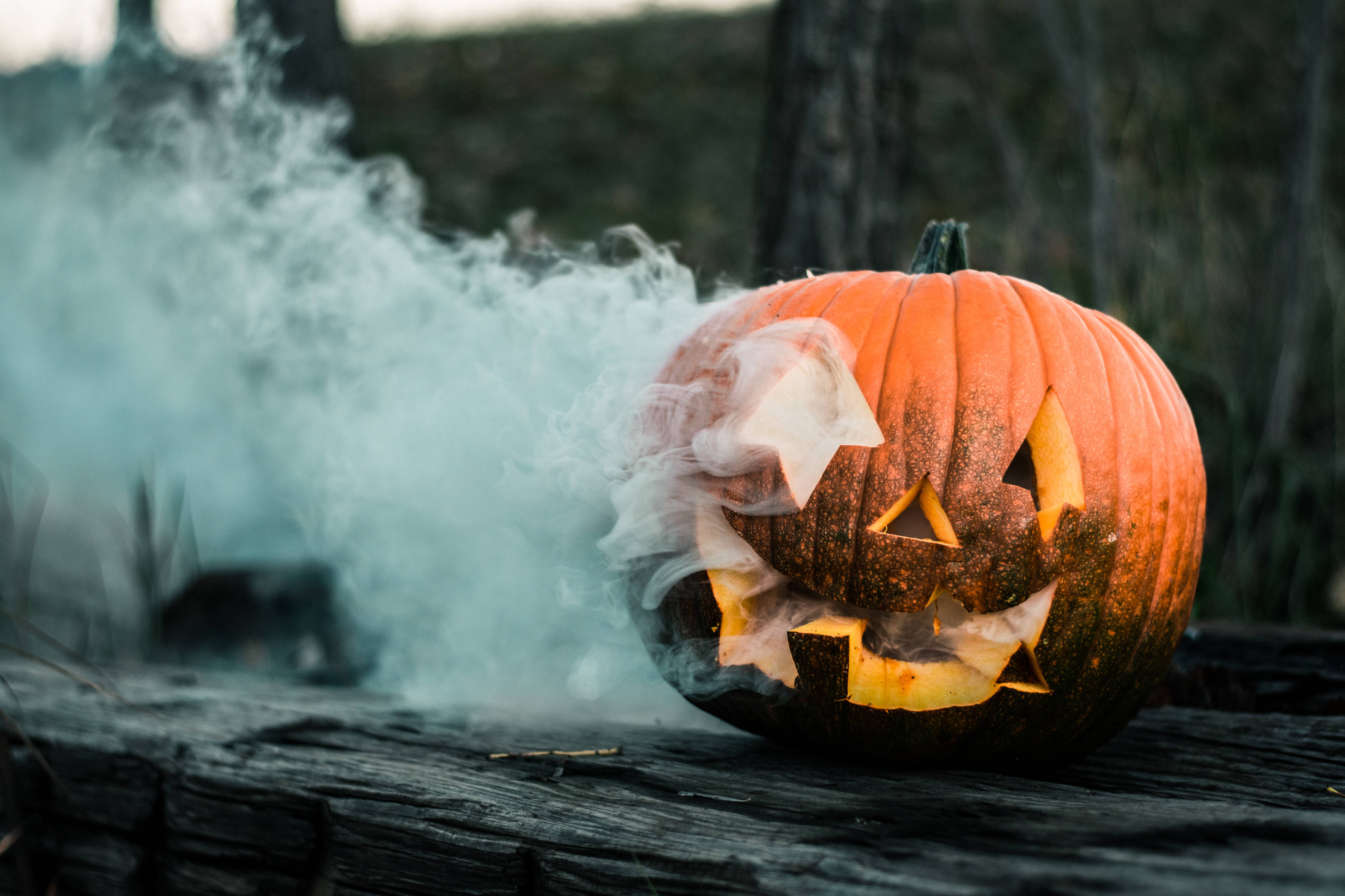 white smoke, carved orange pumpkin, glowing eyes and mouth, 4K Desktop Wallpaper
