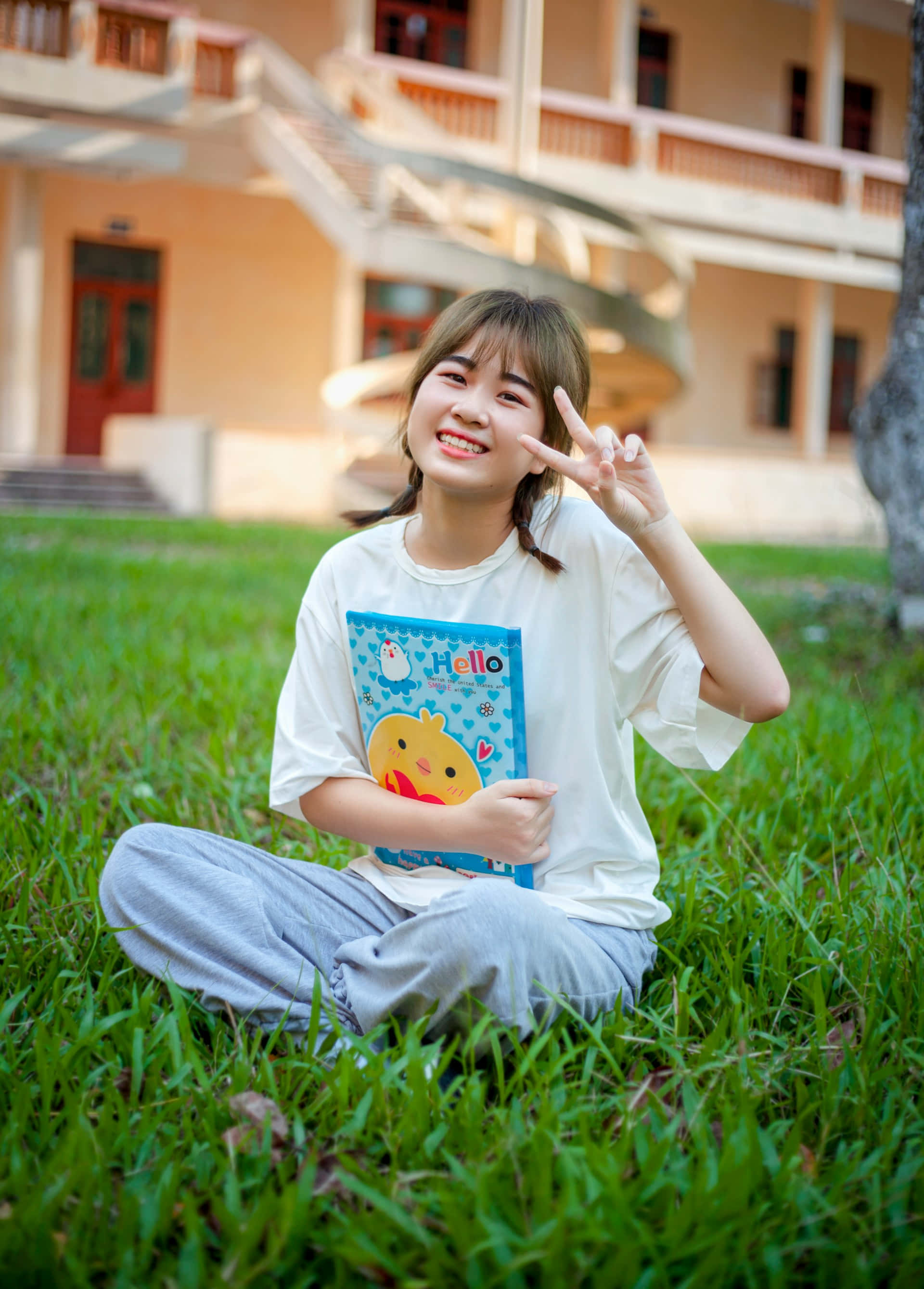 smiling young woman, vibrant green grass, blue notebook, 2K Phone Wallpaper