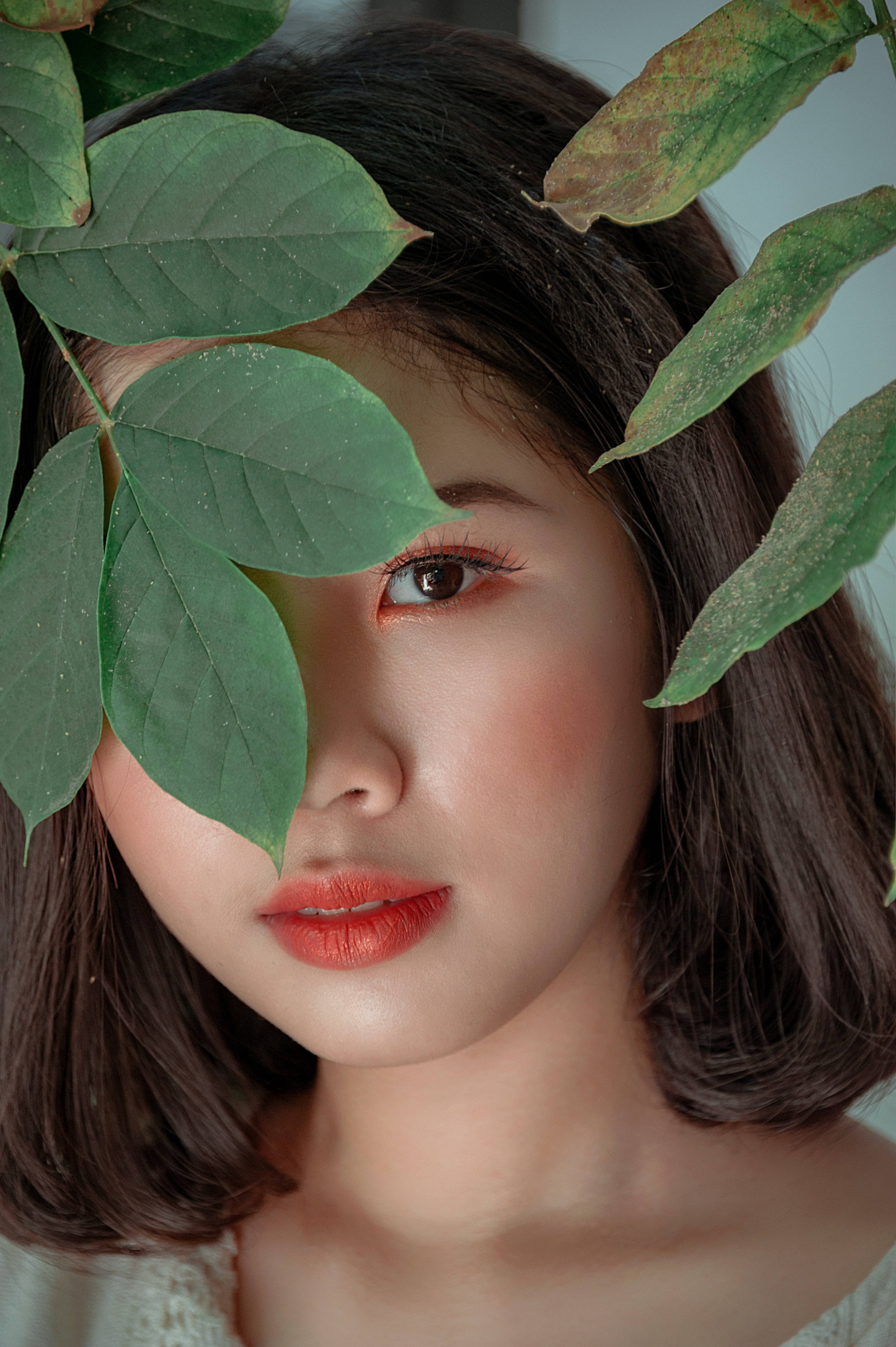 red lips, one eye visible, lush green leaves, 4K Phone Wallpaper