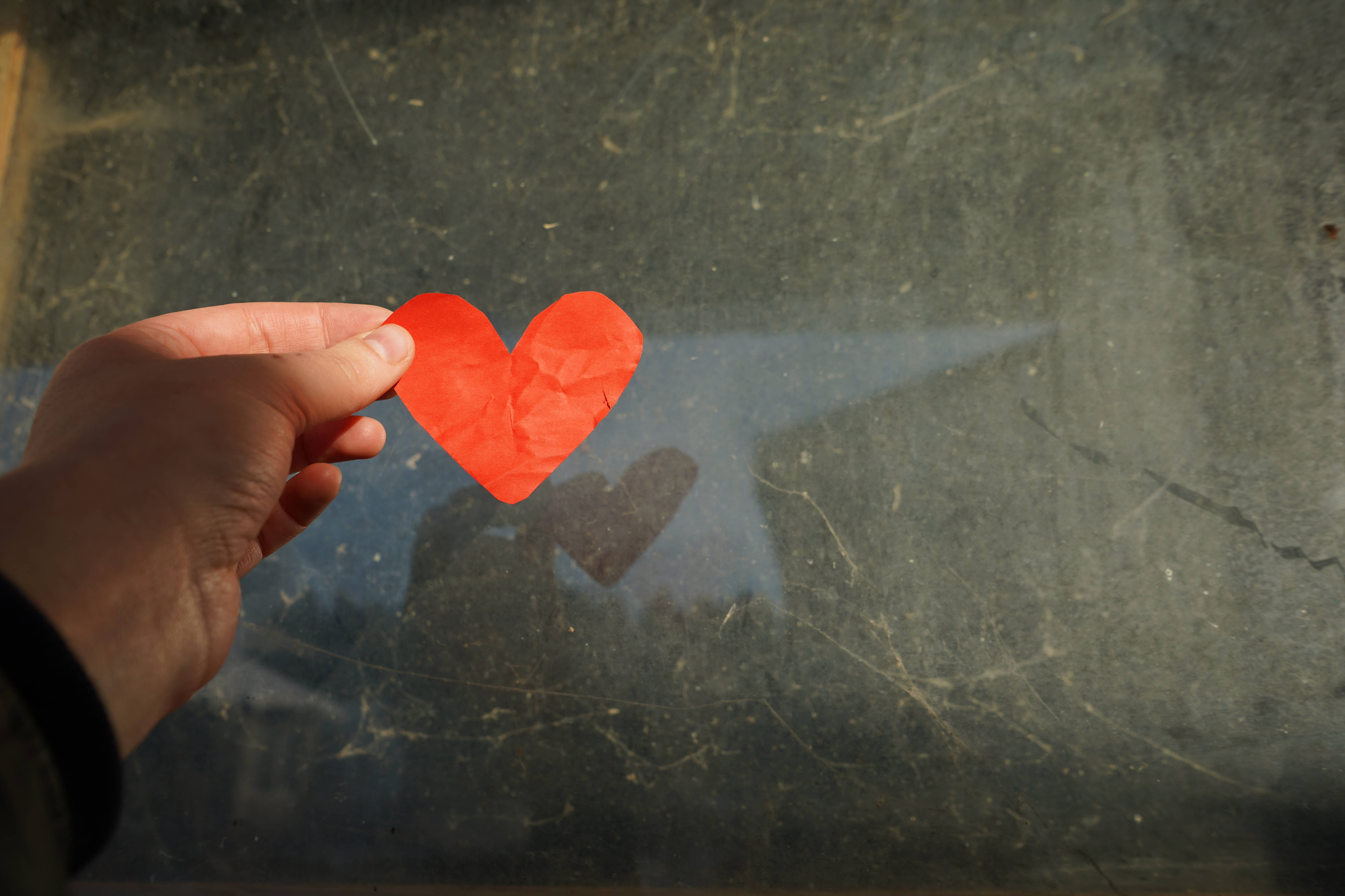 bright red paper heart, scratched glass window, soft sunlight, 5K Desktop Wallpaper