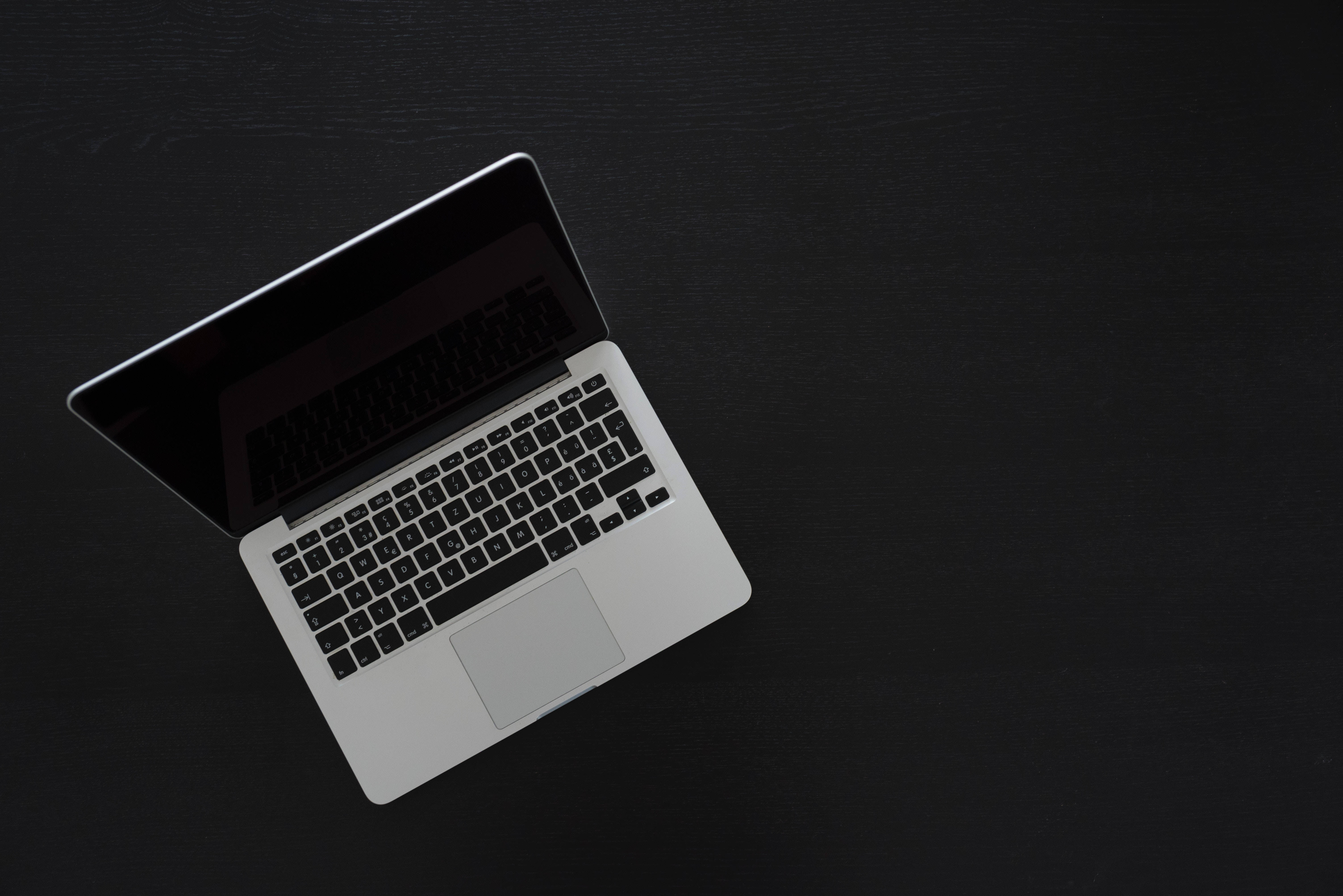 sleek silver laptop, matte black textured surface, minimalist composition, 5K Desktop Wallpaper