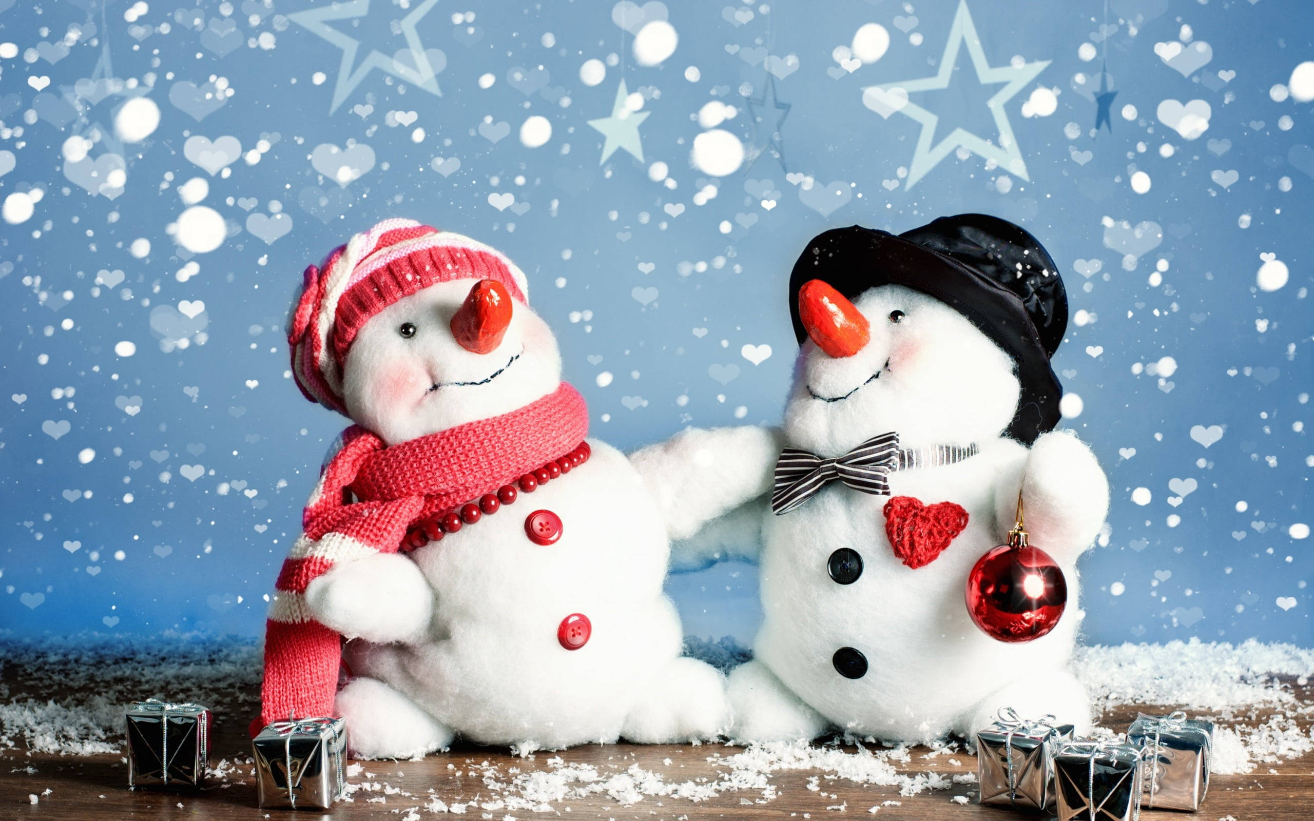 snowman figurines, festive red and black accessories, snowy wooden surface, 2K Desktop Wallpaper