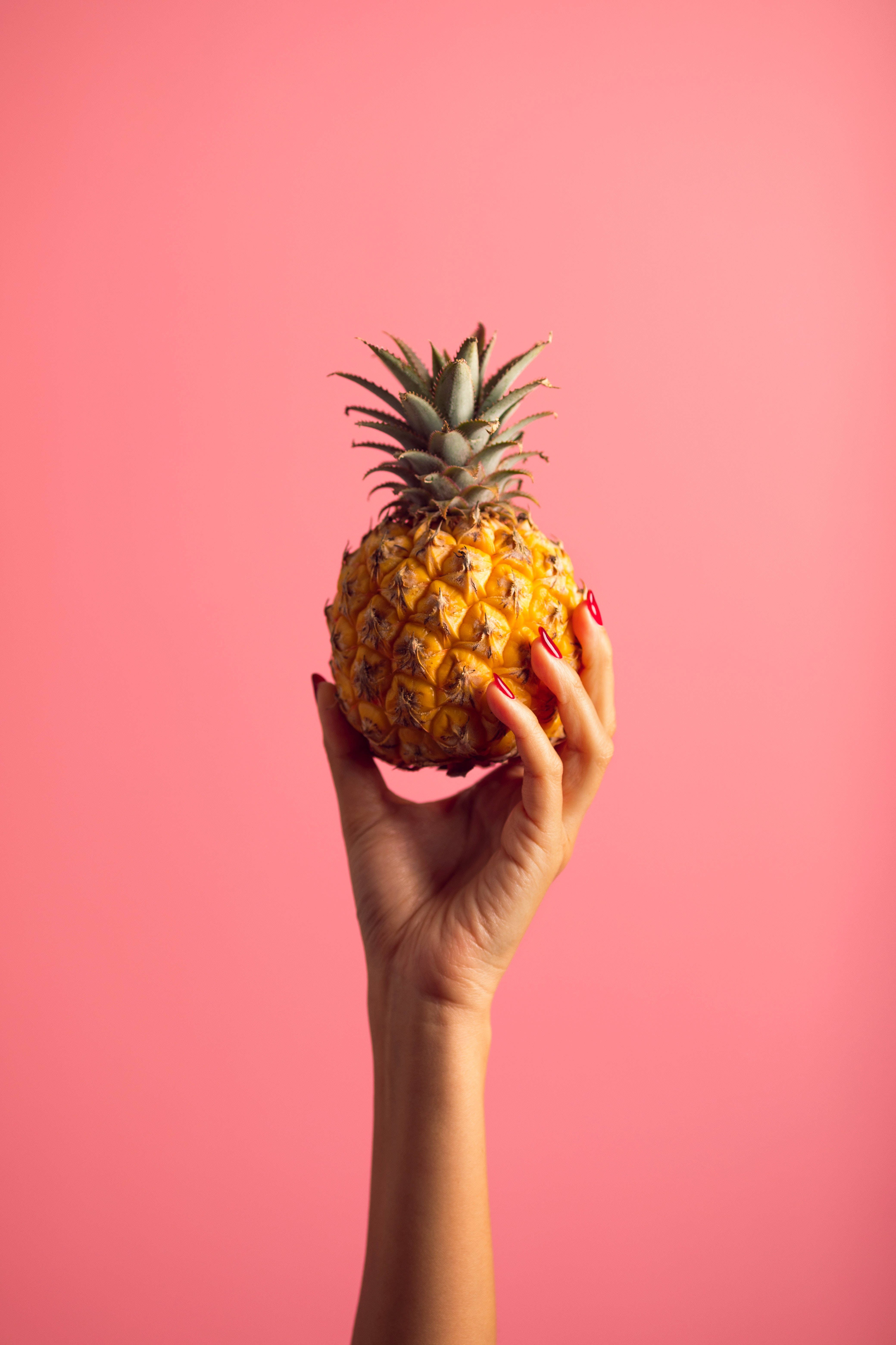 small pineapple, pink background, hand with red nails, 5K Phone Wallpaper