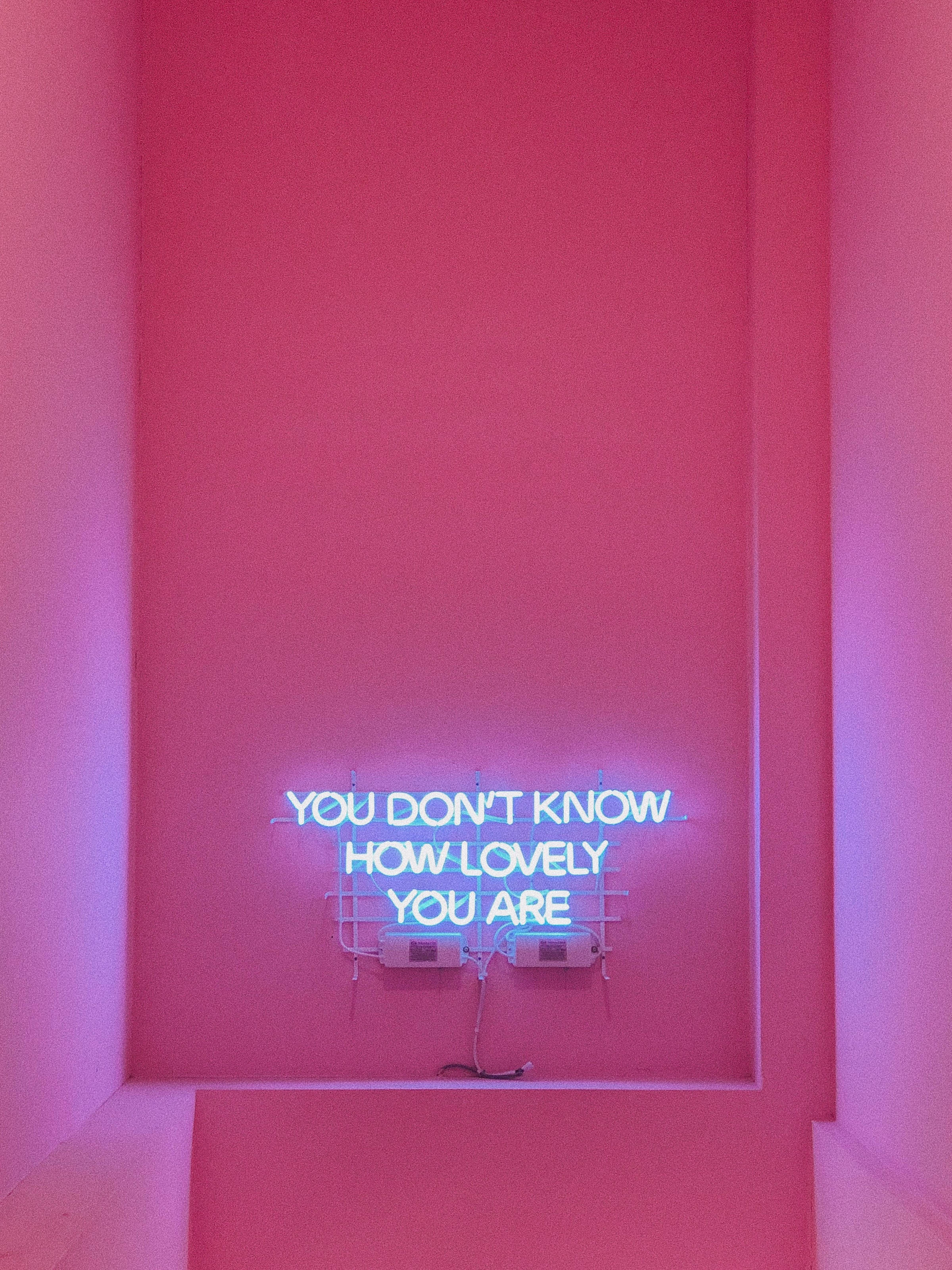 YOU DON'T KNOW HOW LOVELY YOU ARE, glowing blue neon sign, vibrant pink wall, 2K Phone Wallpaper