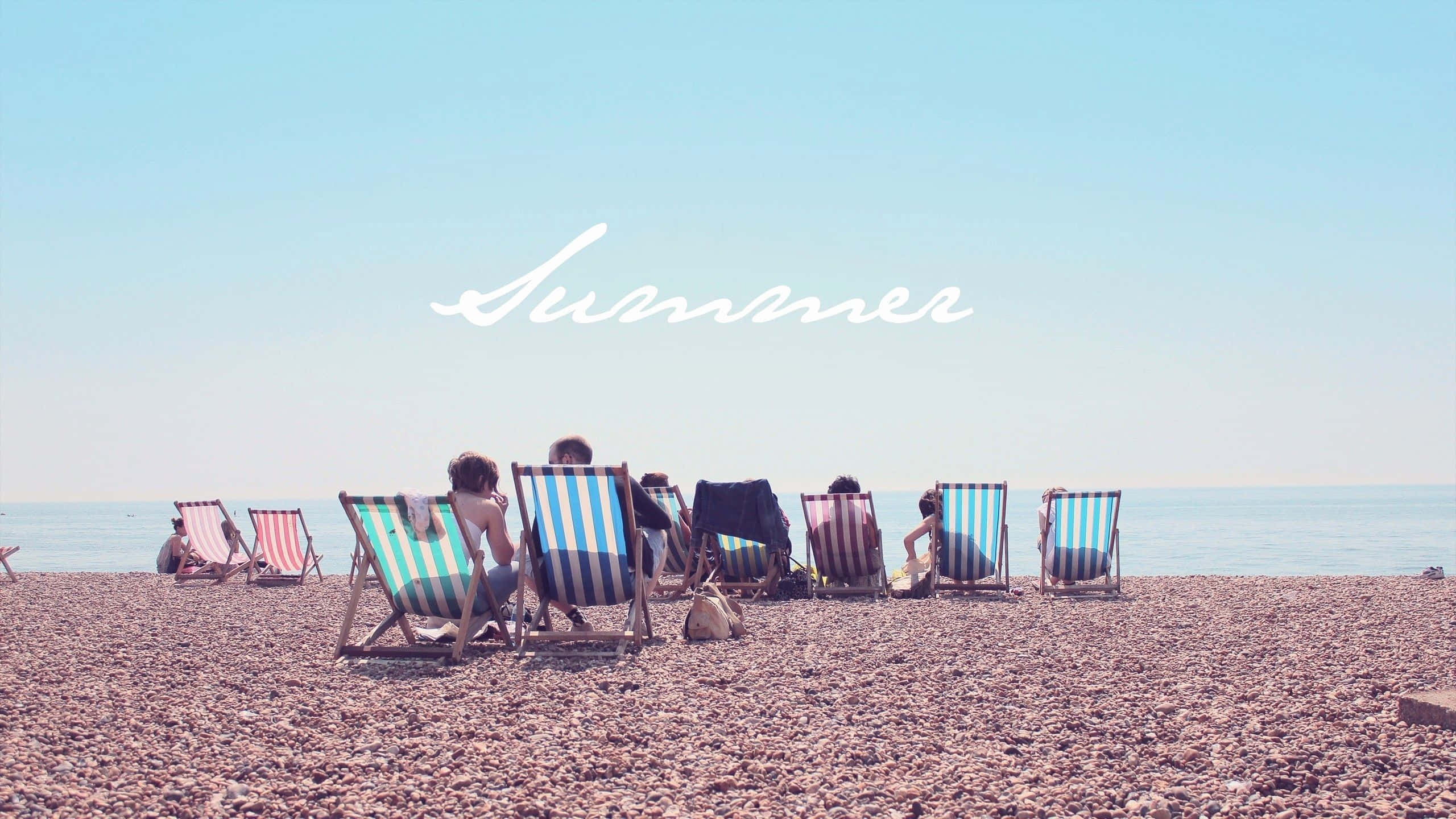 pebbled beach, striped deck chairs, clear blue sky, 2K Desktop Wallpaper