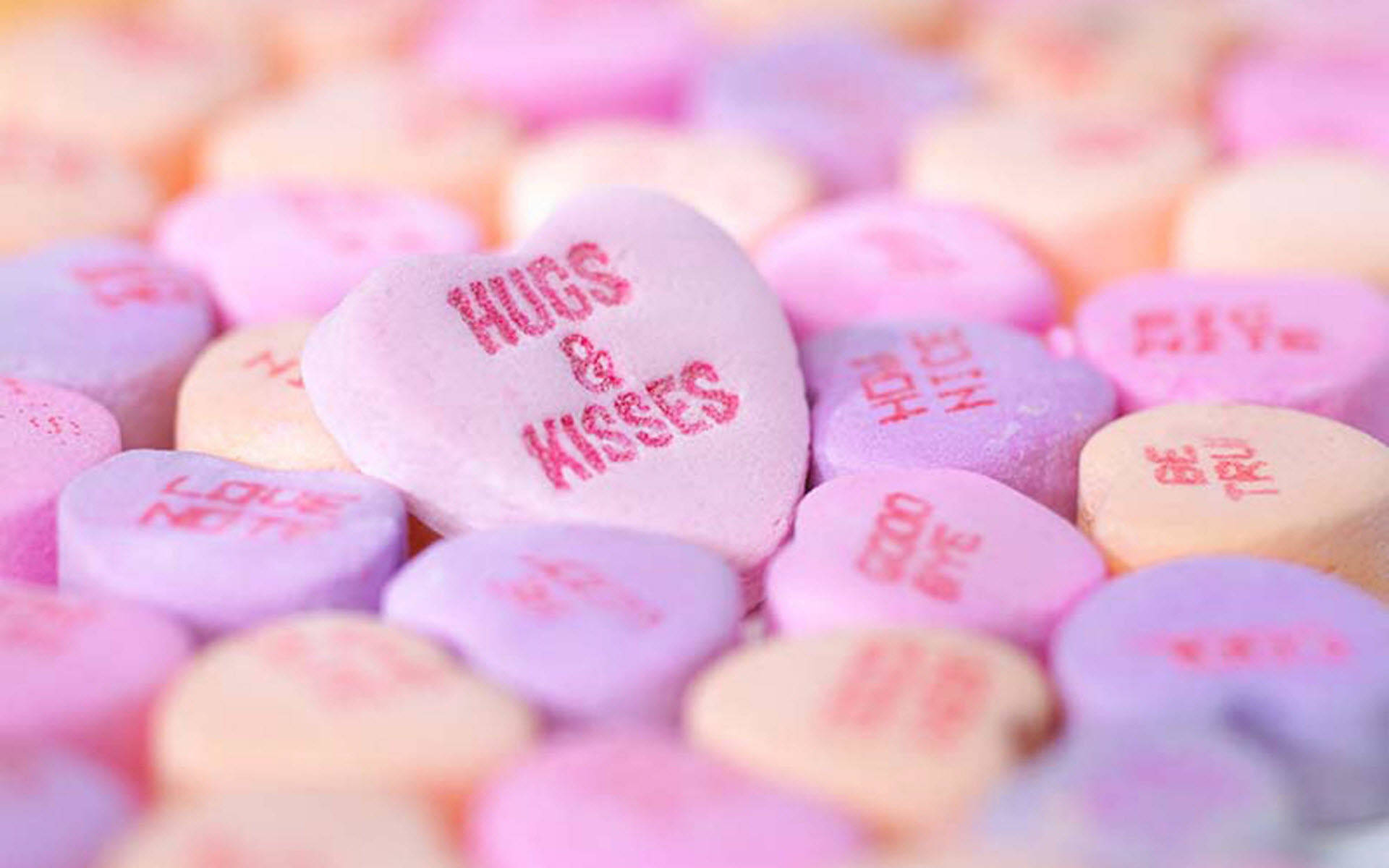 pastel heart-shaped candies, red messages like hugs kisses, shallow depth of field, Full HD Desktop Wallpaper