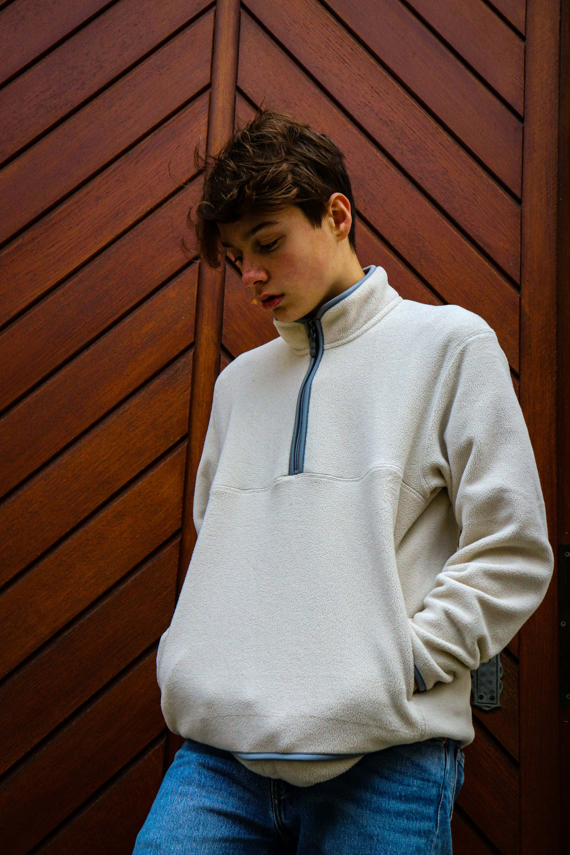 cream fleece pullover, rich brown wooden slat wall, contemplative teen, 2K Phone Wallpaper