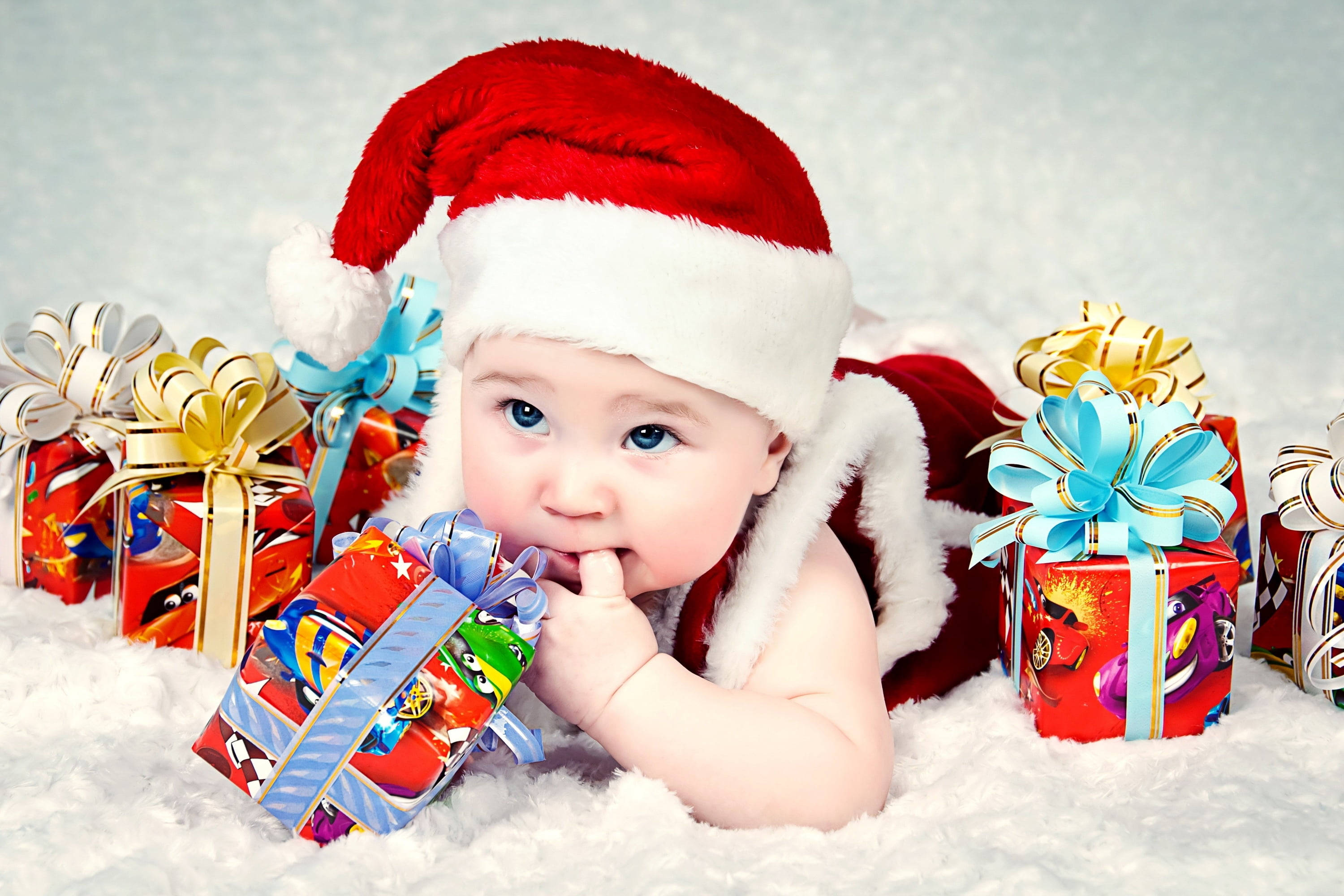 red Santa hat, snowy white fur, colorful gift boxes with bows, 2K Desktop Wallpaper