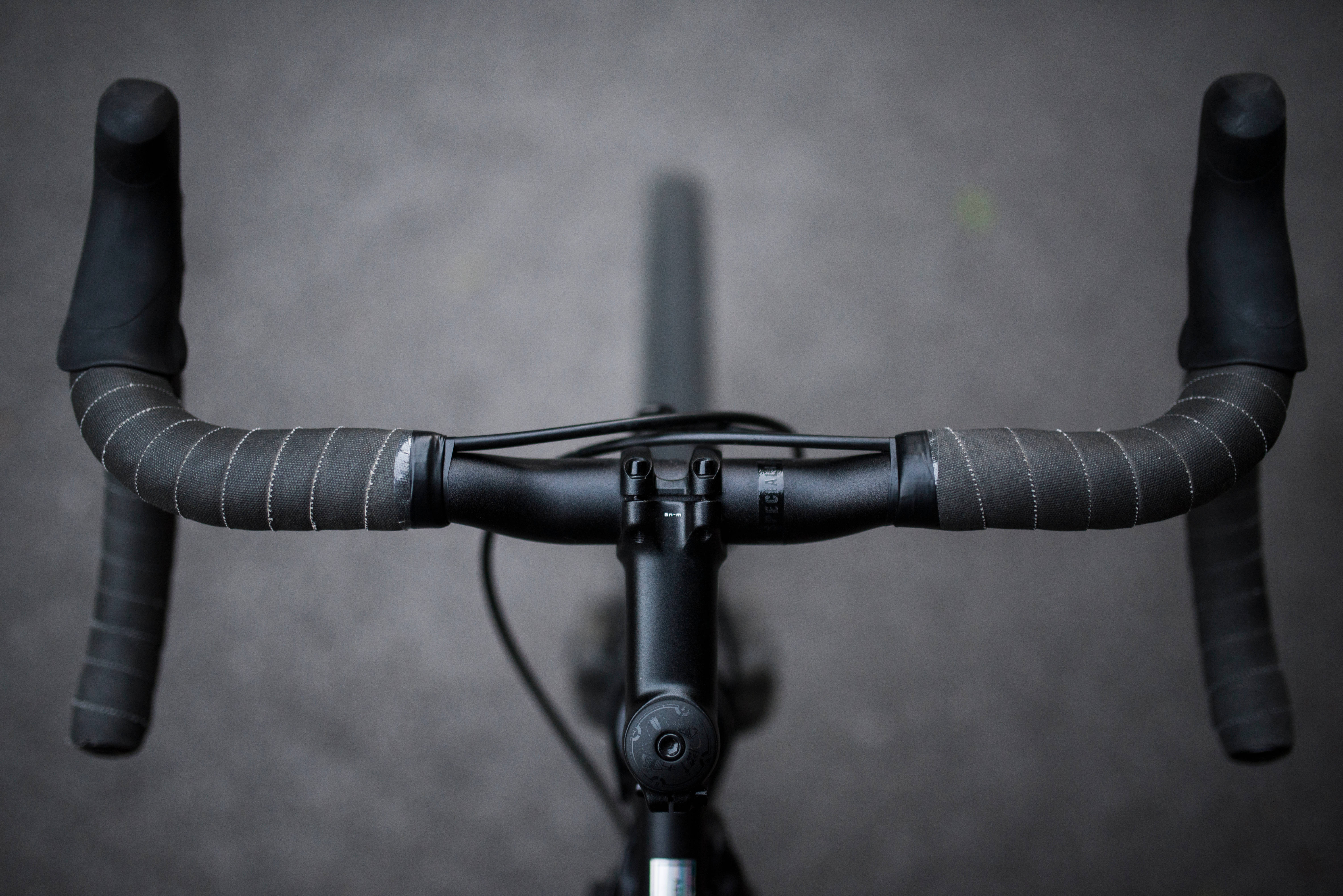sleek black road bike handlebar, textured grips, muted gray background, 5K Desktop Wallpaper