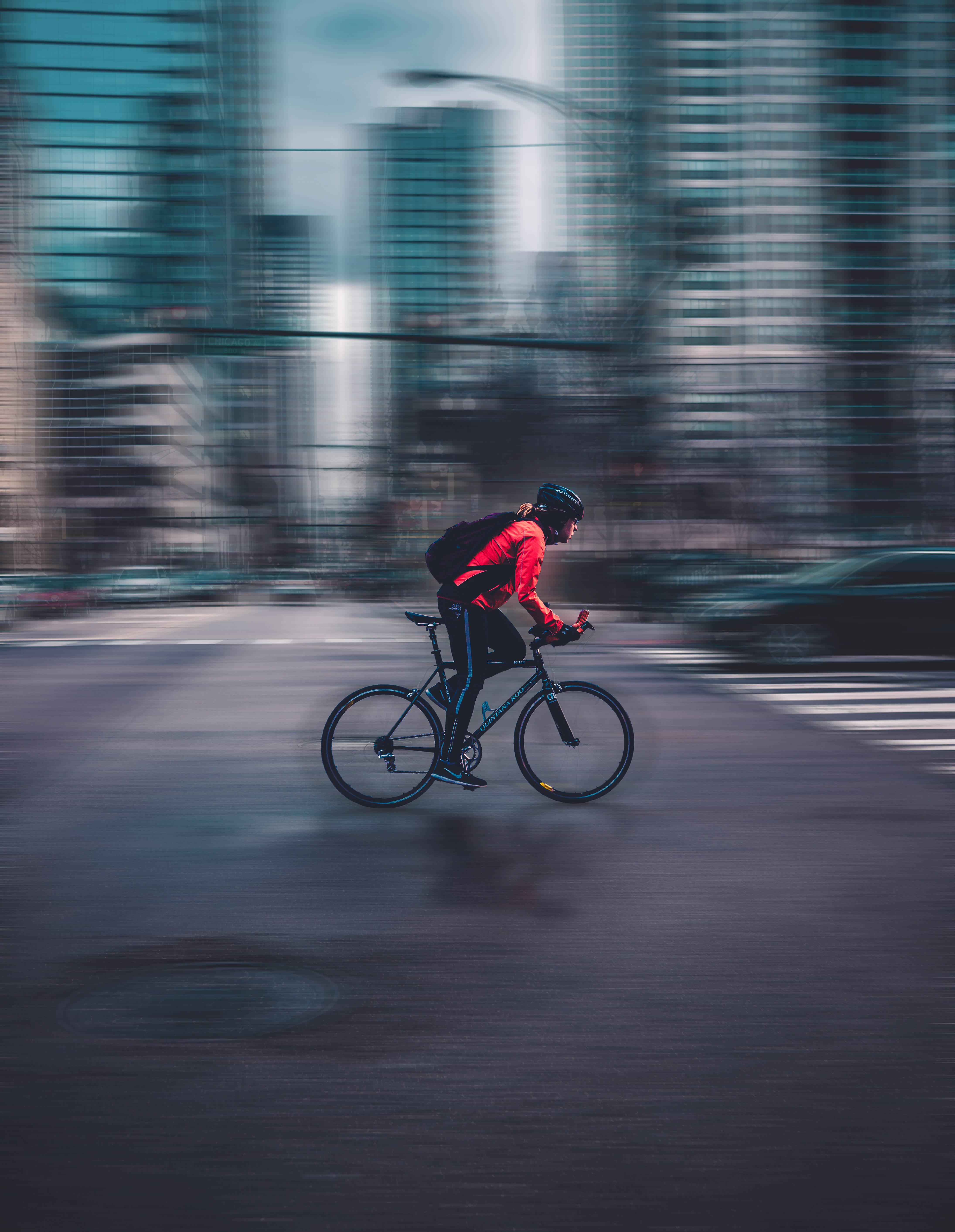 red jacket, blurred urban street, towering glass skyscrapers, 5K Phone Wallpaper