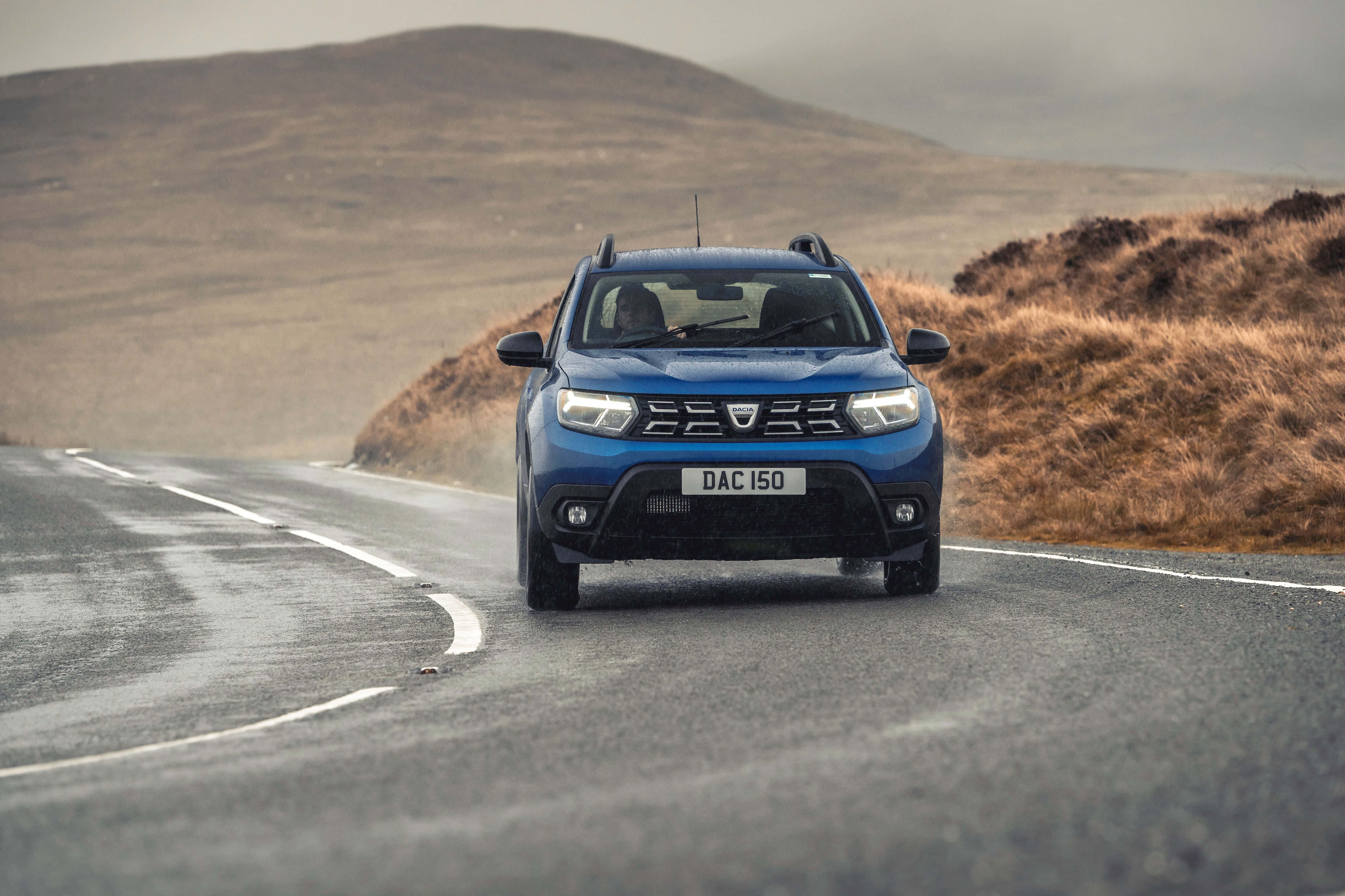 blue Dacia Duster, wet winding road, barren hills, 4K Desktop Wallpaper