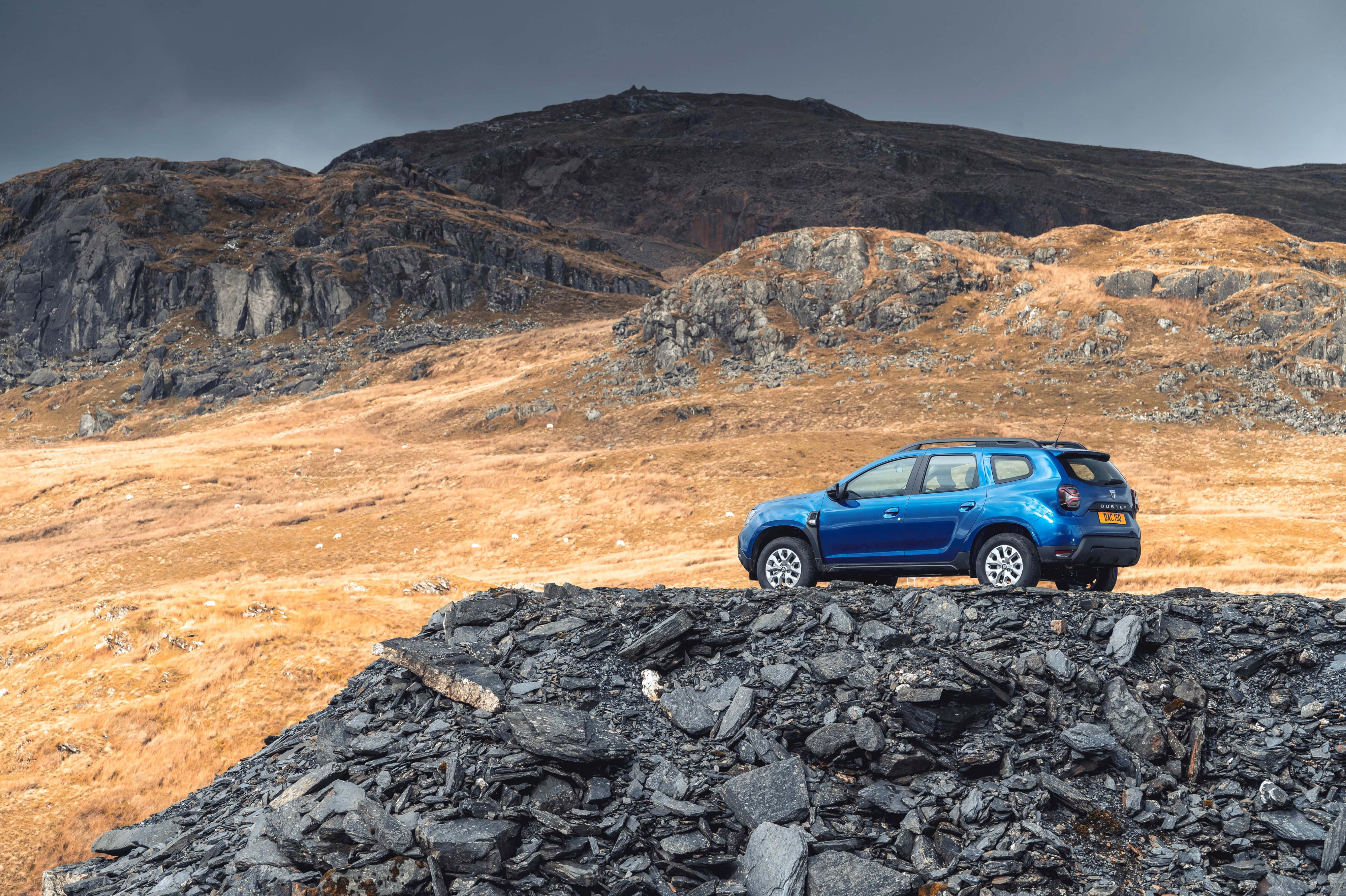 Blue Dacia Duster, mountainous terrain, jagged stone ridge, 4K Desktop Wallpaper