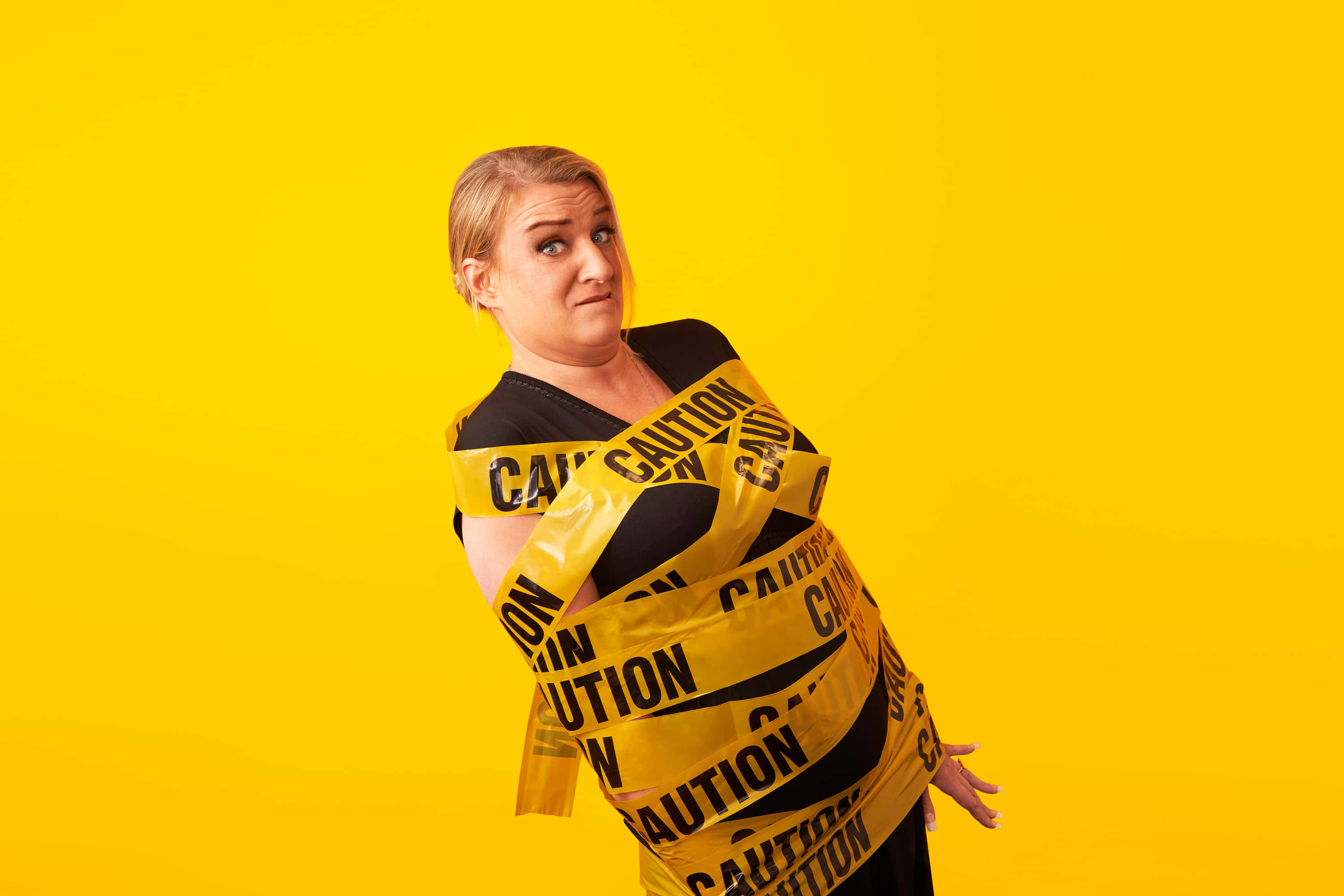 Daisy May Cooper, yellow caution tape, bright yellow background, 2K Desktop Wallpaper