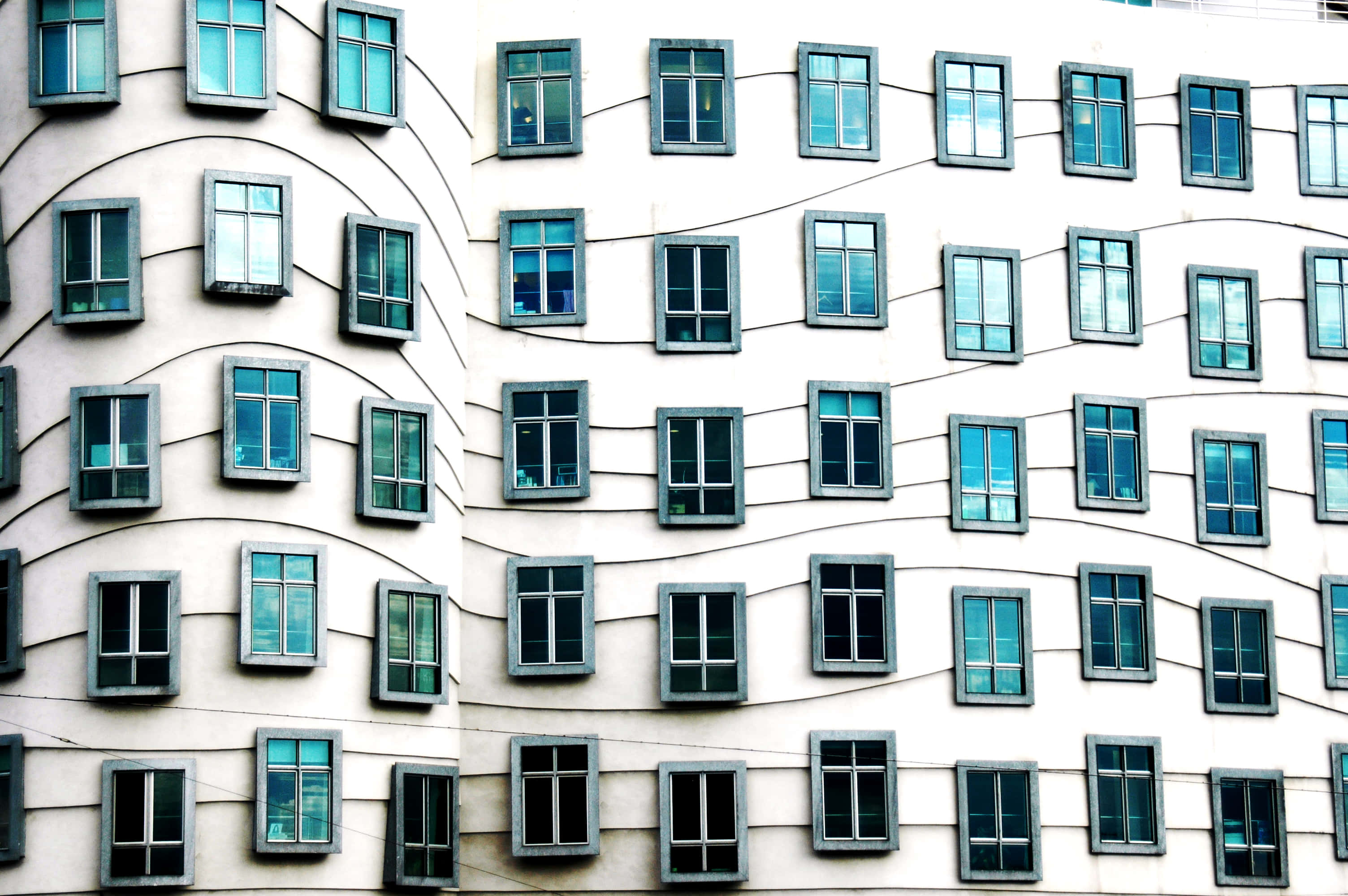 Dancing House, curved white walls, blue-tinted windows, 2K Desktop Wallpaper