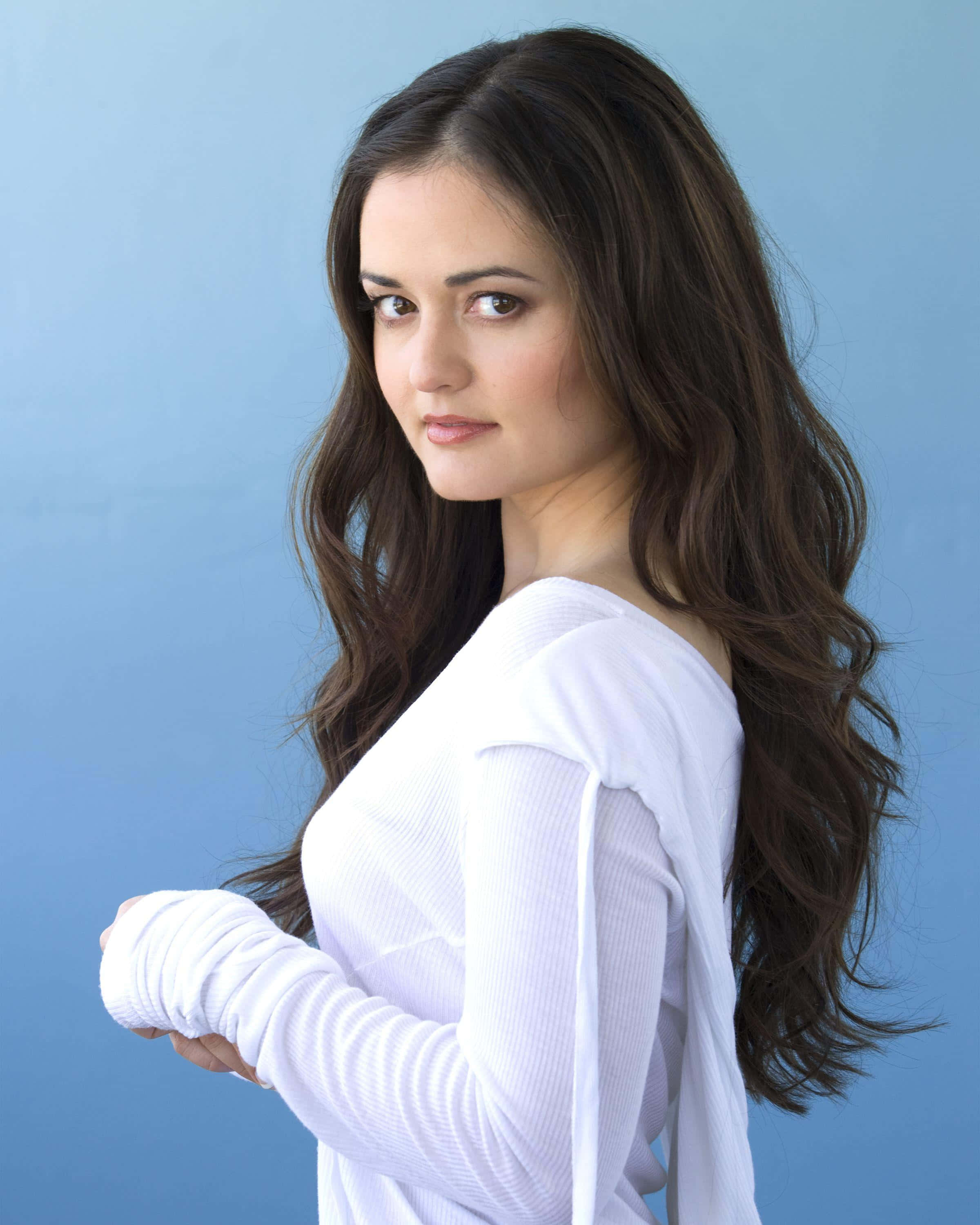 Danica Mckellar, white ribbed top, solid blue studio background, 2K Phone Wallpaper
