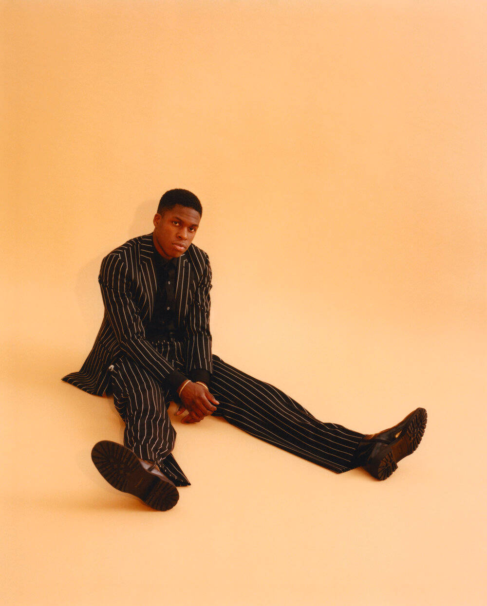 Daniel Caesar, black pinstripe suit, warm peach floor, SD Phone Wallpaper