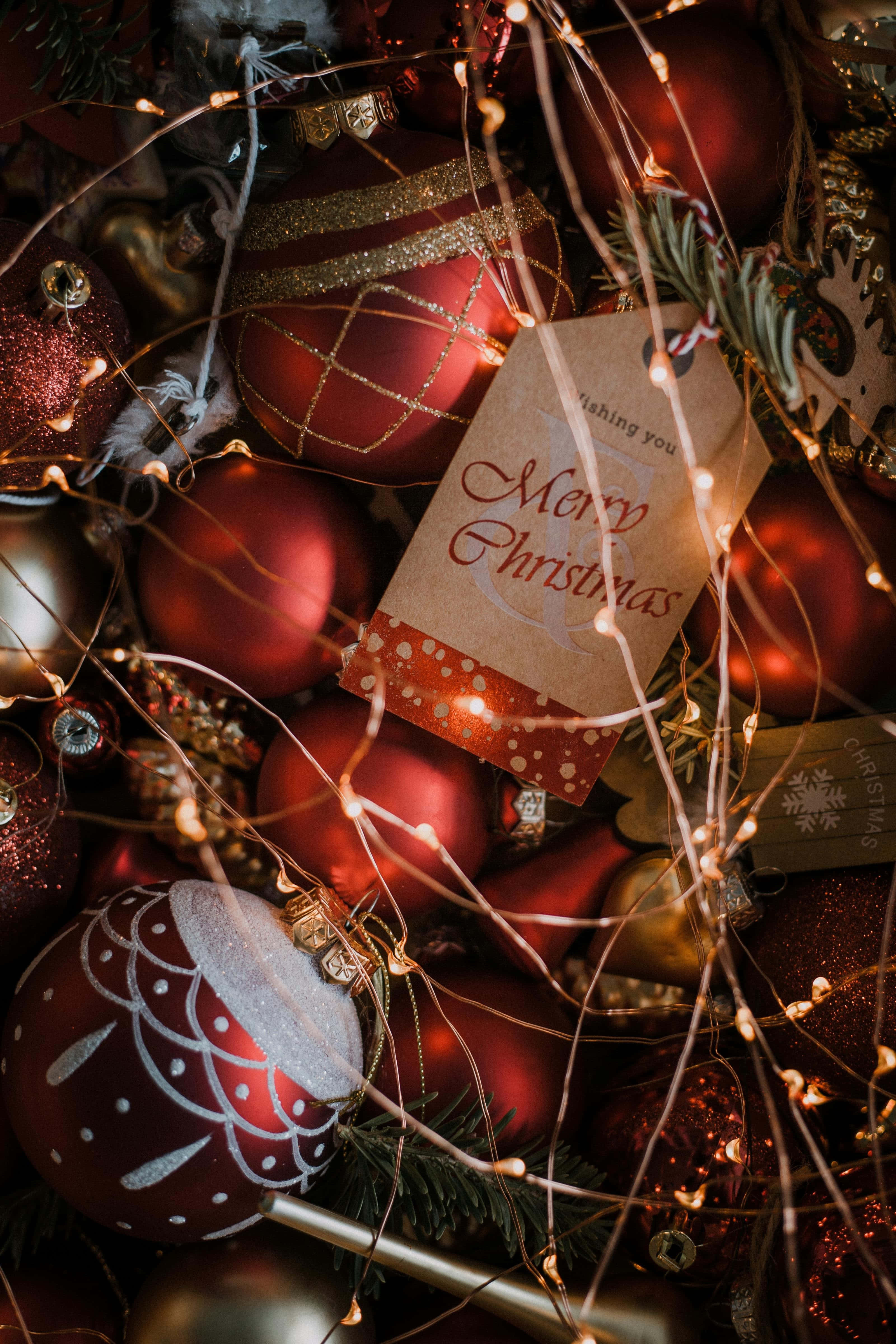 red Christmas ornaments, warm fairy lights, handwritten 'Merry Christmas' tag, 4K Phone Wallpaper