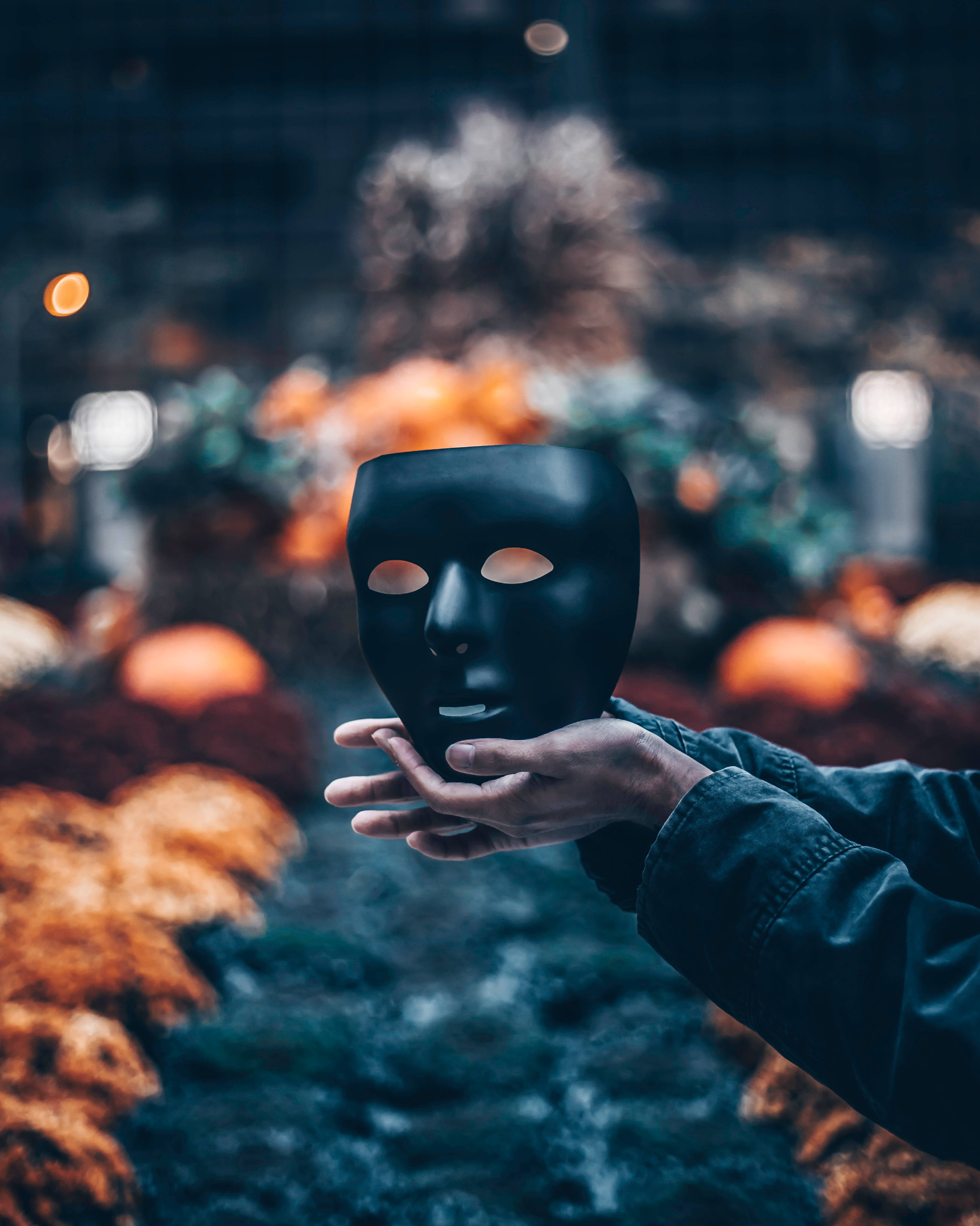 black theatrical mask, autumnal background, warm orange and teal tones, 4K Phone Wallpaper