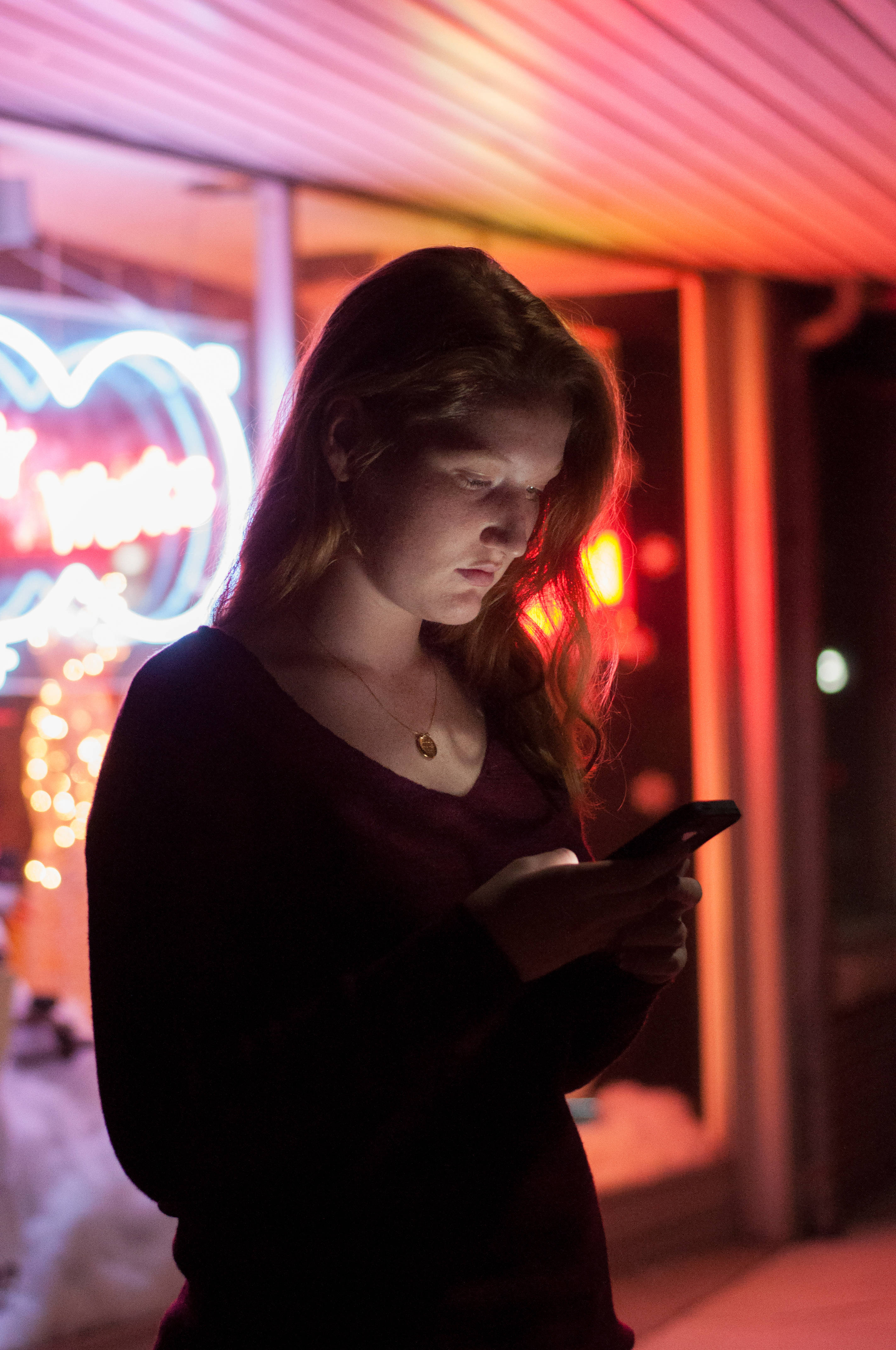 Dark Neon iPhone, neon-lit urban night scene, young woman, 4K Phone Wallpaper