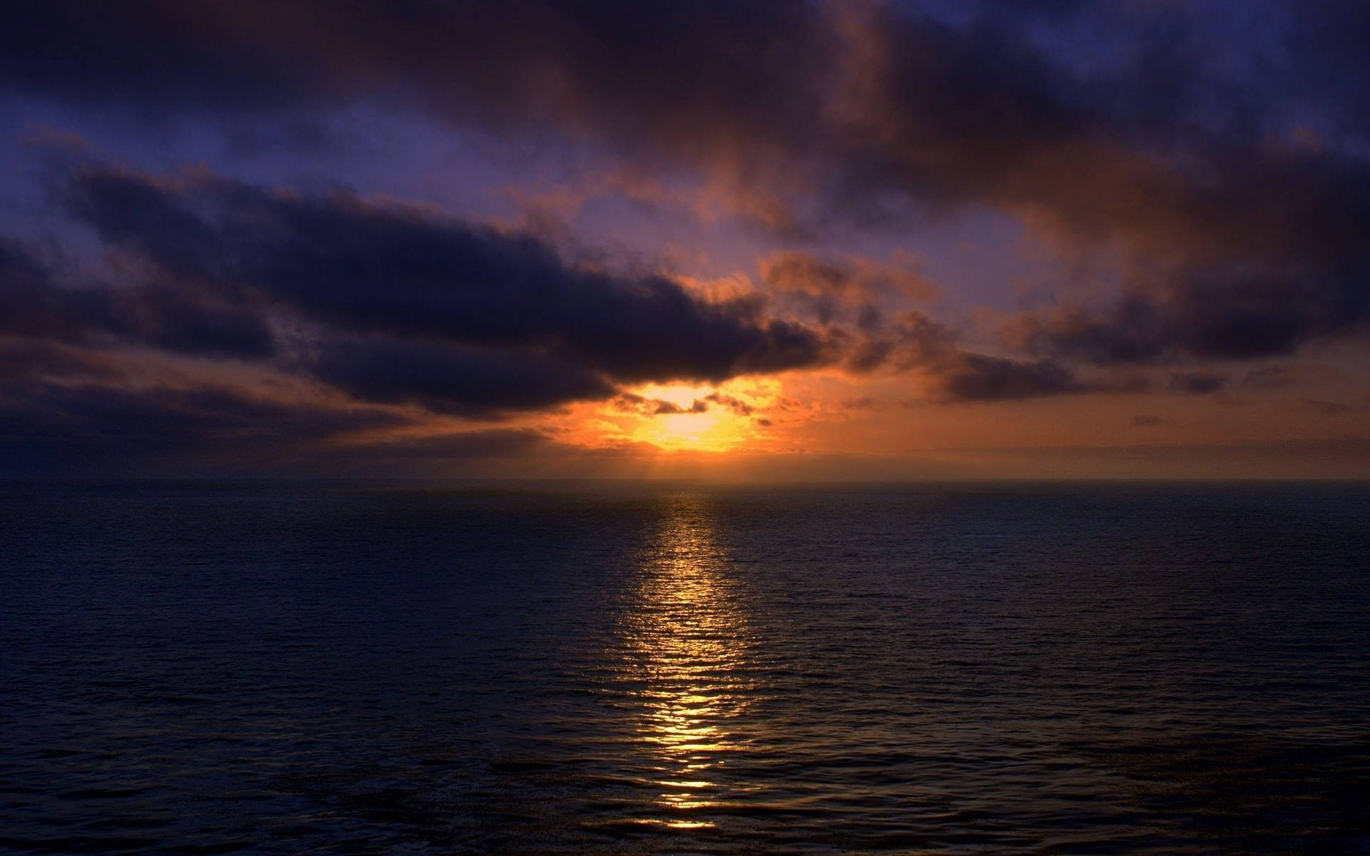 Darkening Sunset Ocean, fiery orange sun, dark purple clouds, Full HD Desktop Wallpaper