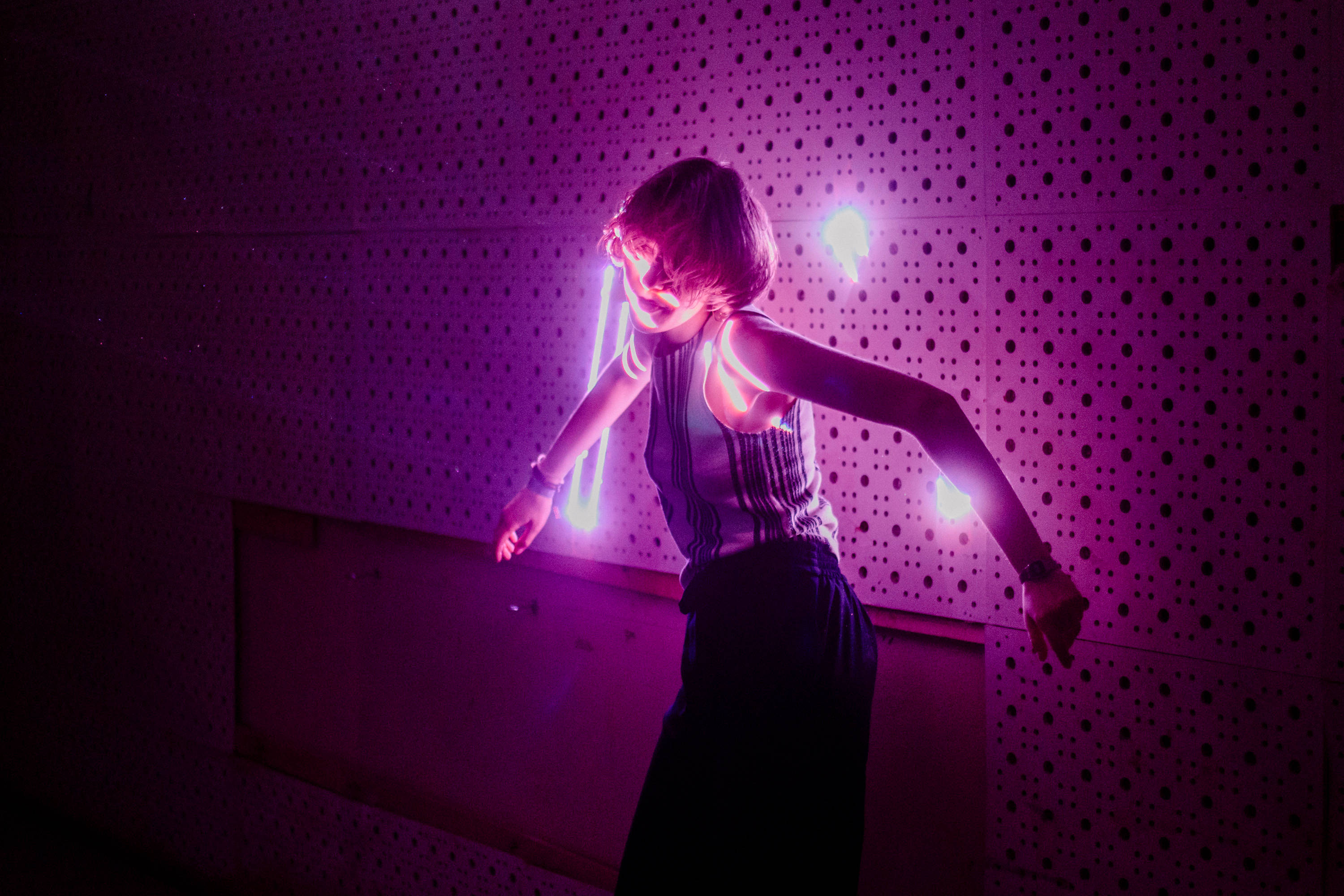 vibrant purple neon lights, perforated wall, woman dancing, 2K Desktop Wallpaper