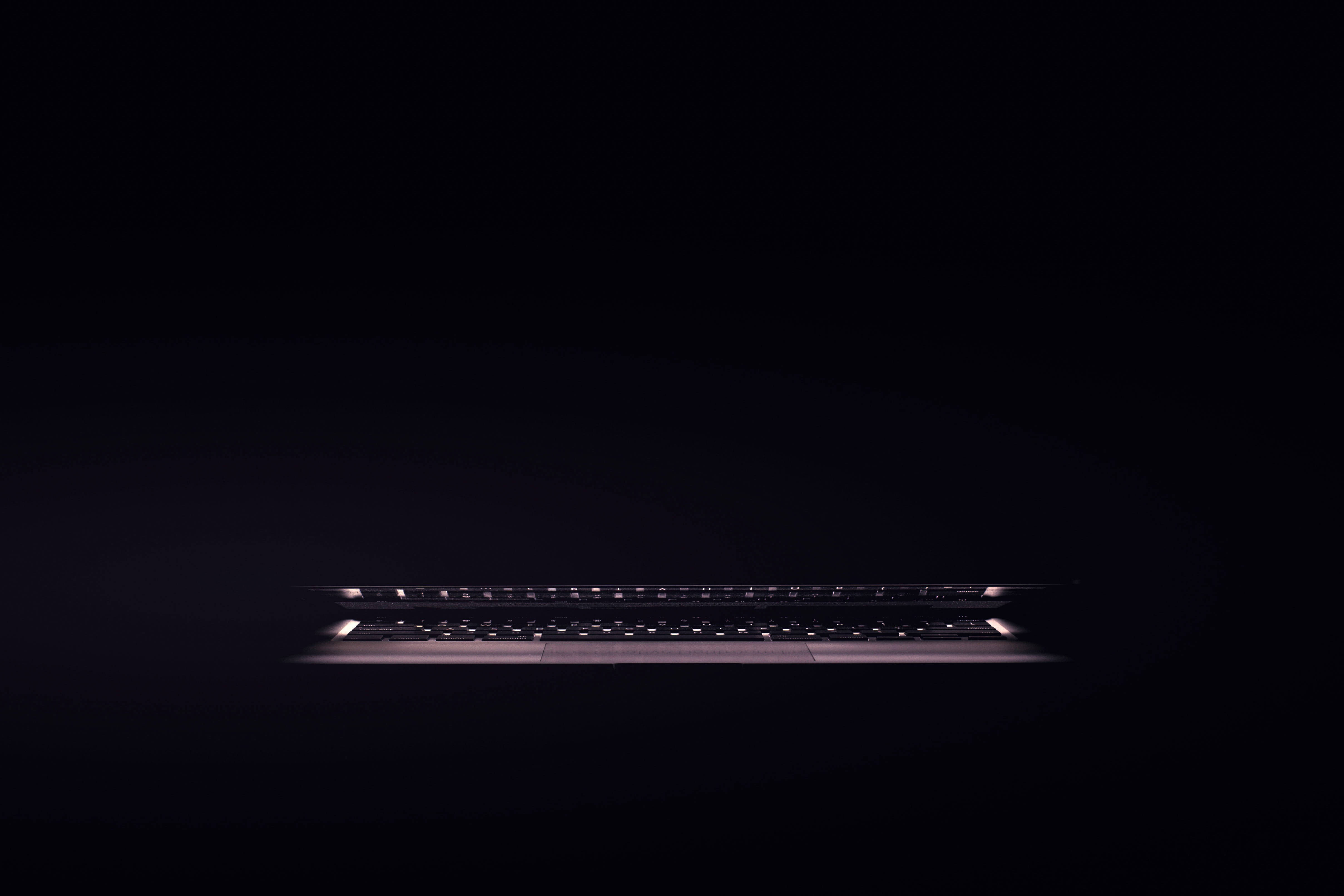 dark laptop keyboard, glows softly, pitch-black background, 4K Desktop Wallpaper