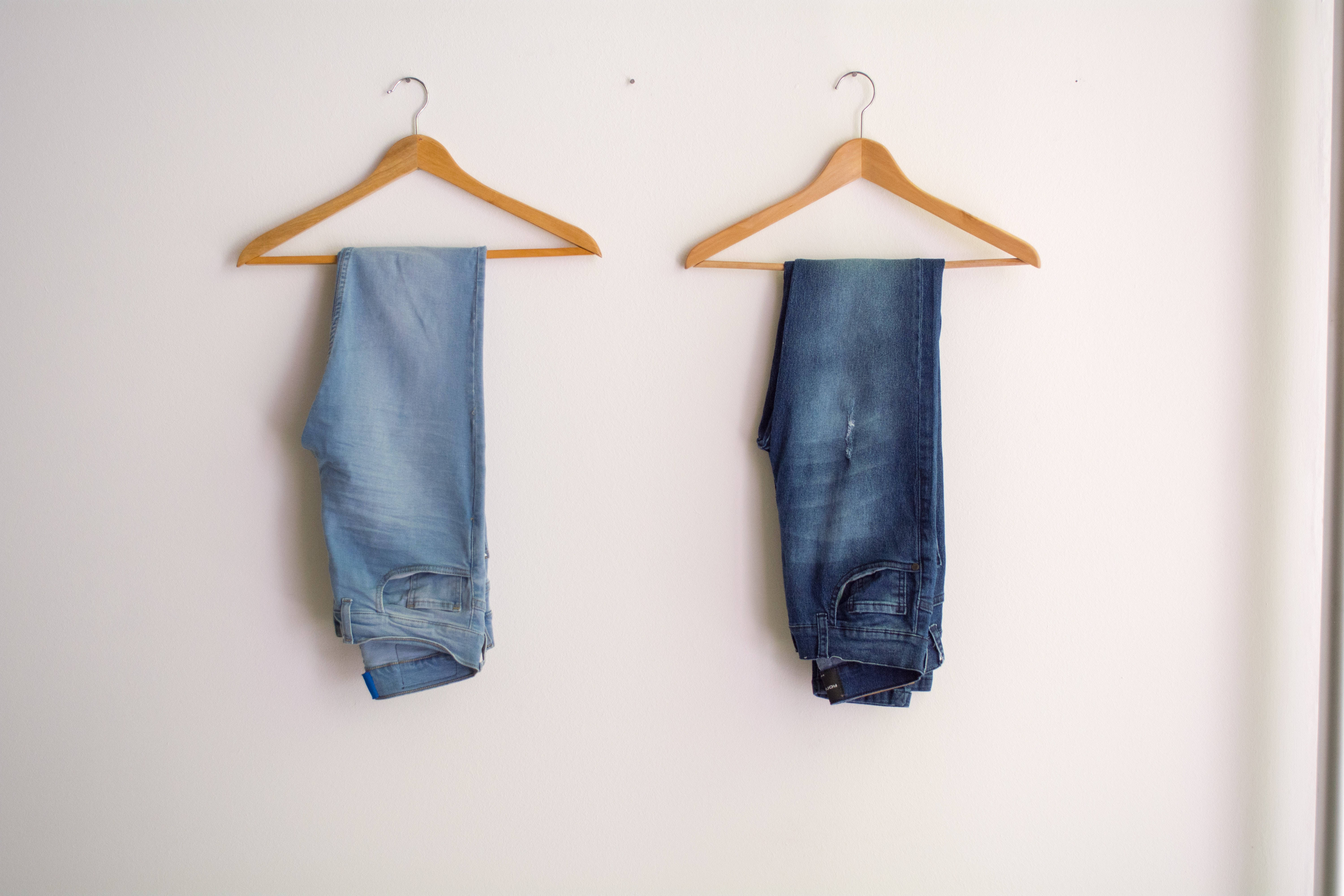 dark blue denim jeans, wooden hangers, plain white wall, 5K Desktop Wallpaper