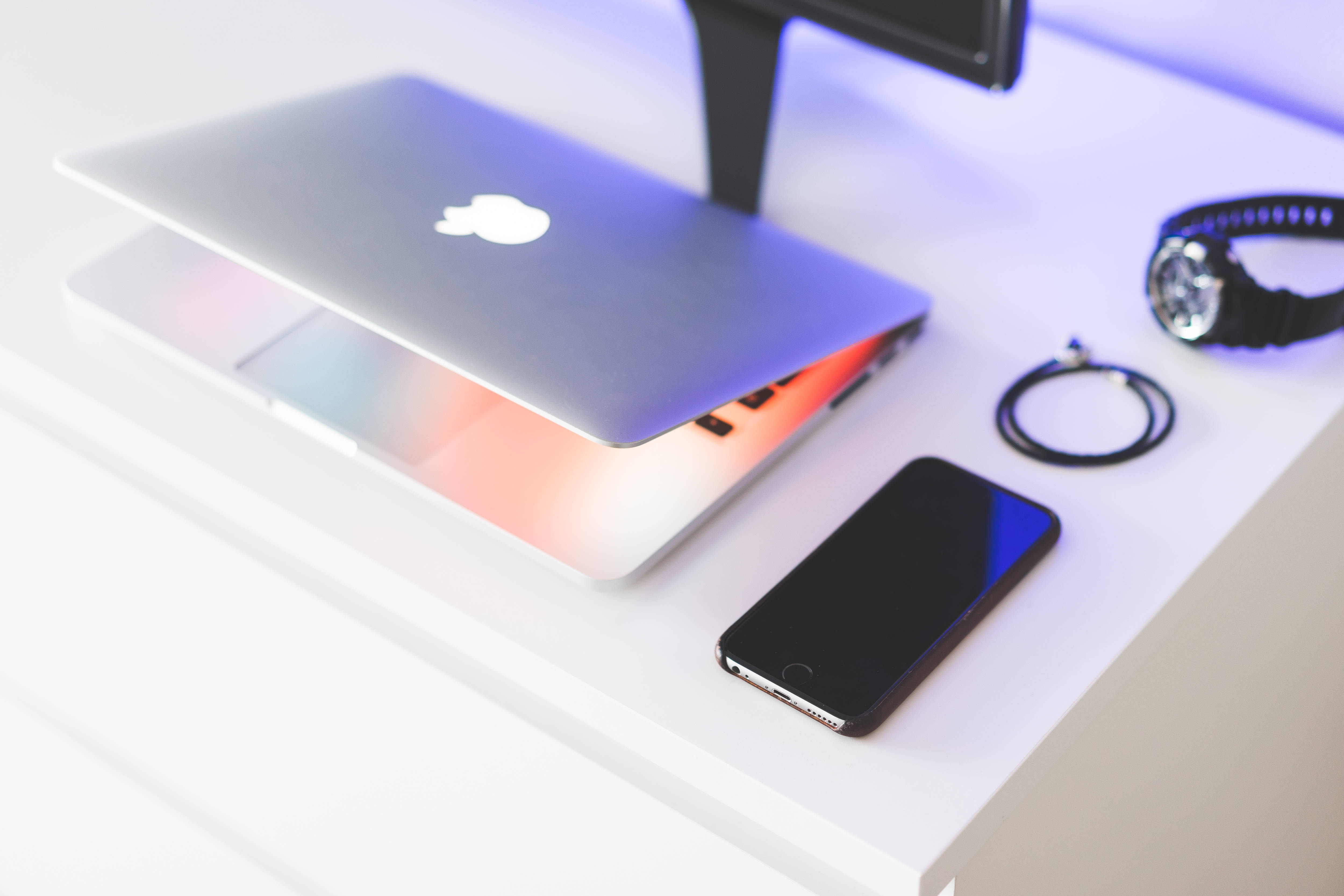 sleek silver laptop, glowing rainbow keyboard, black smartphone watch, 4K Desktop Wallpaper