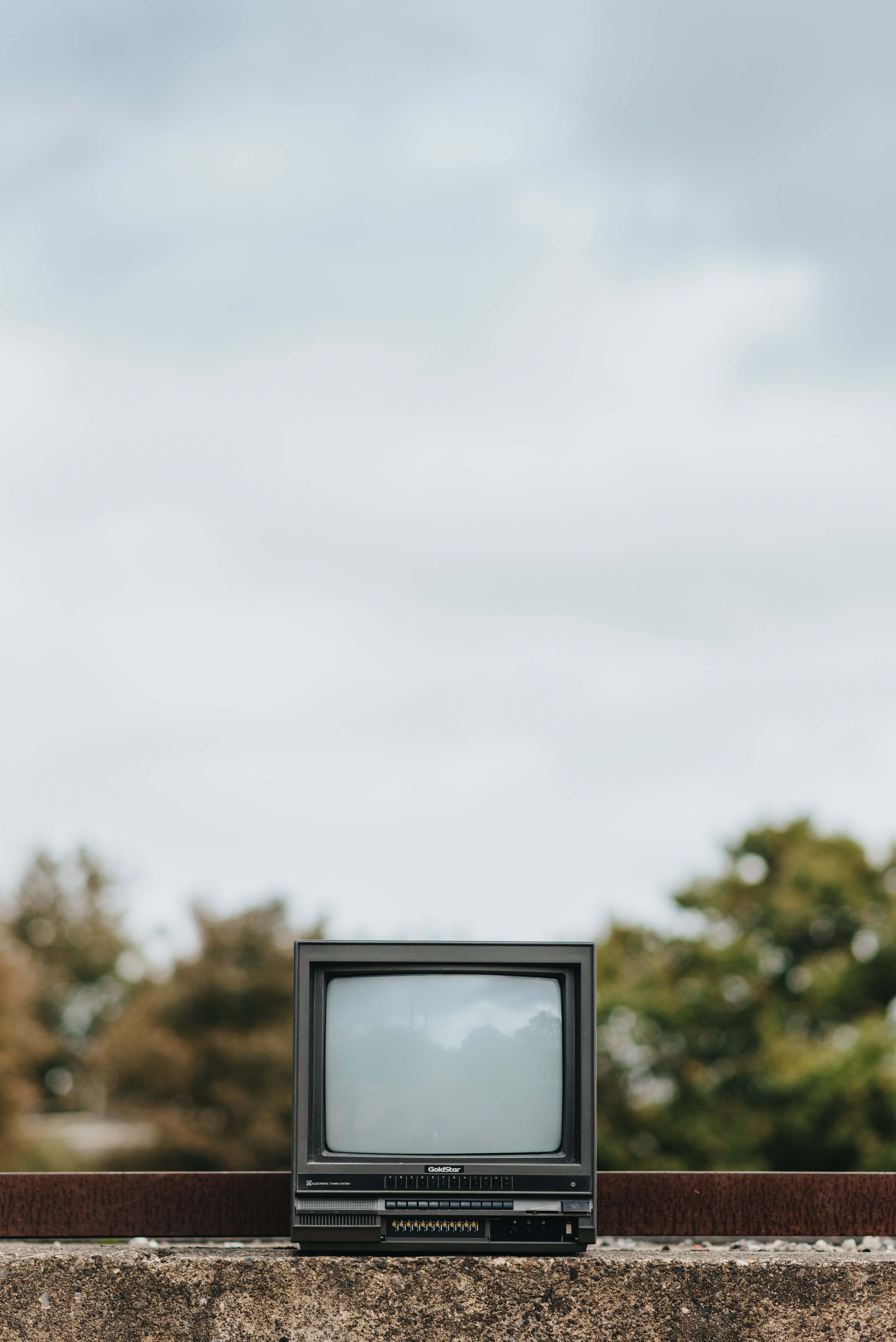 vintage CRT television, concrete ledge, cloudy sky, 5K Phone Wallpaper