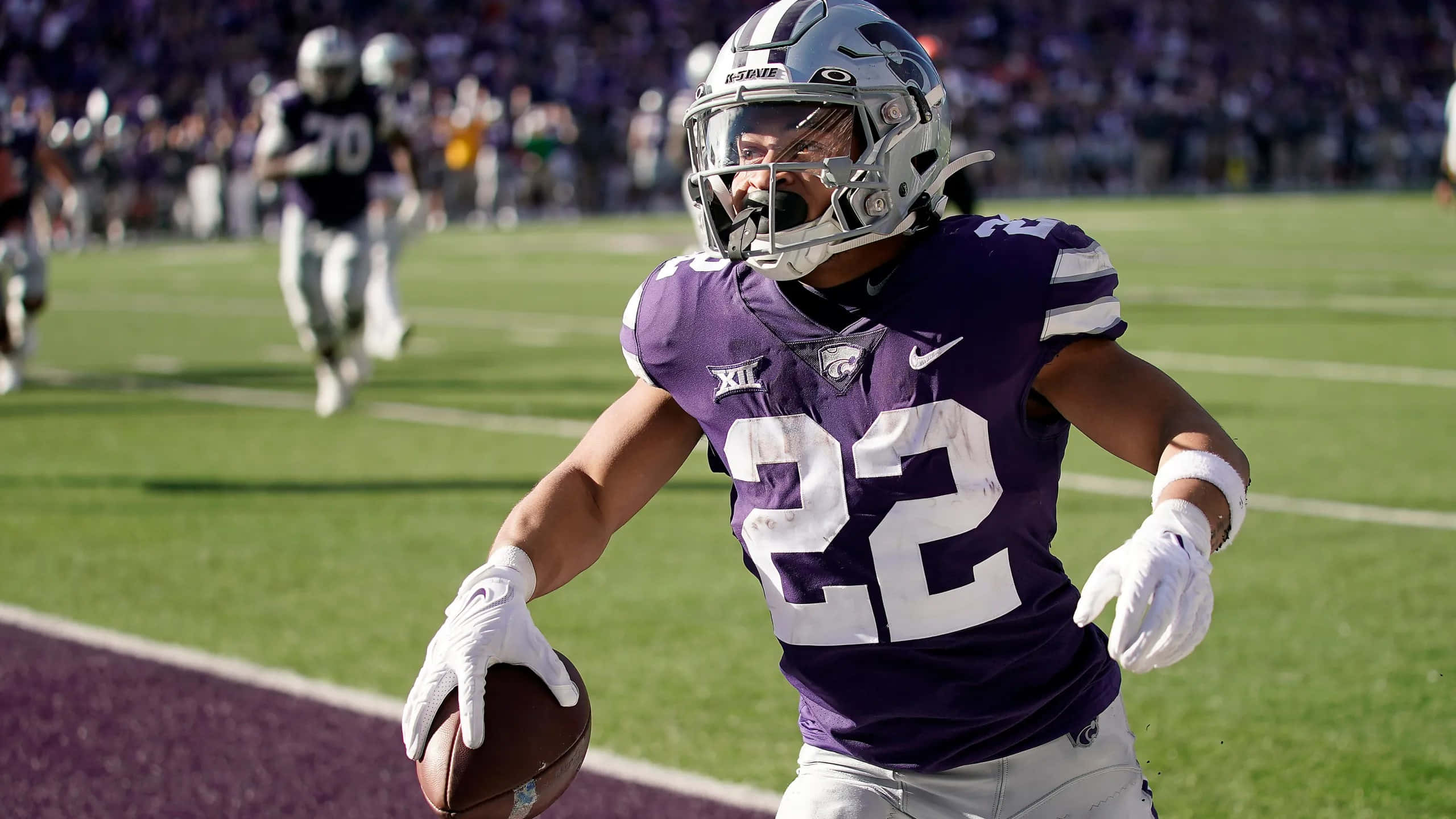 Deuce Vaughn, purple jersey, sunlit field, 2K Desktop Wallpaper