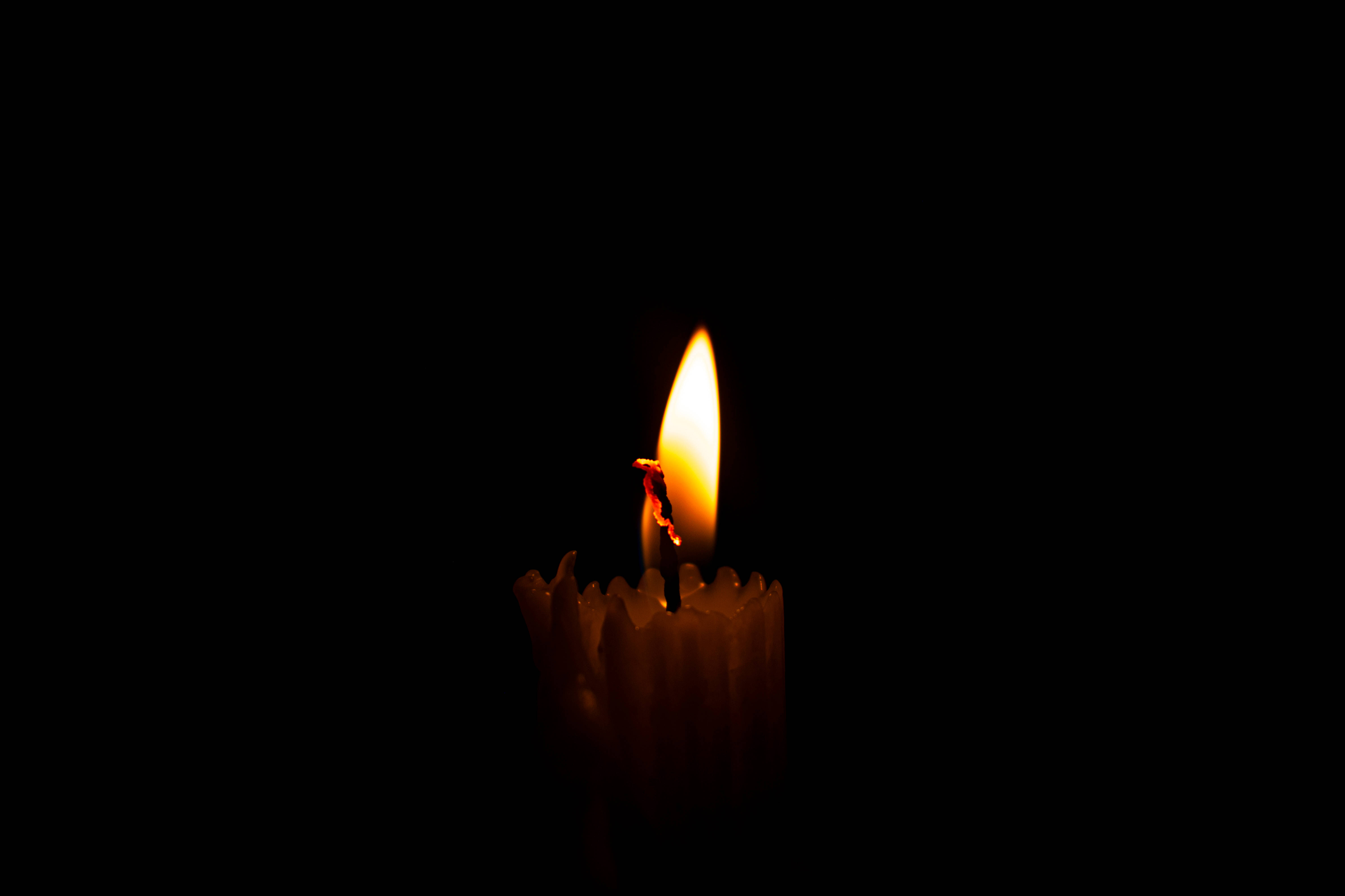 lit candle, warm golden glow, pitch black background, 5K Desktop Wallpaper
